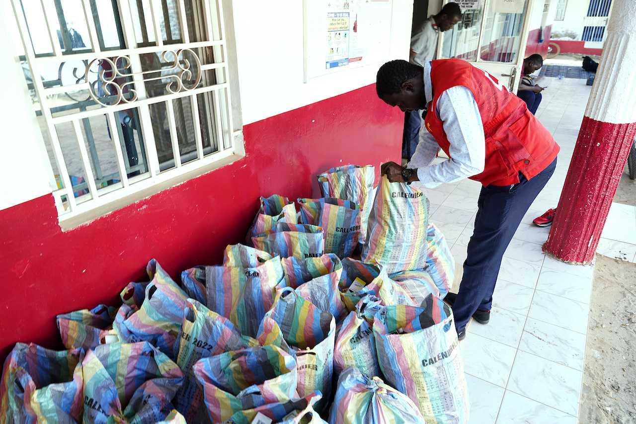A member of the Gambian Red Cross looks through sacks of collected cough syrups in Banjul on Oct 6. Photo: AFP