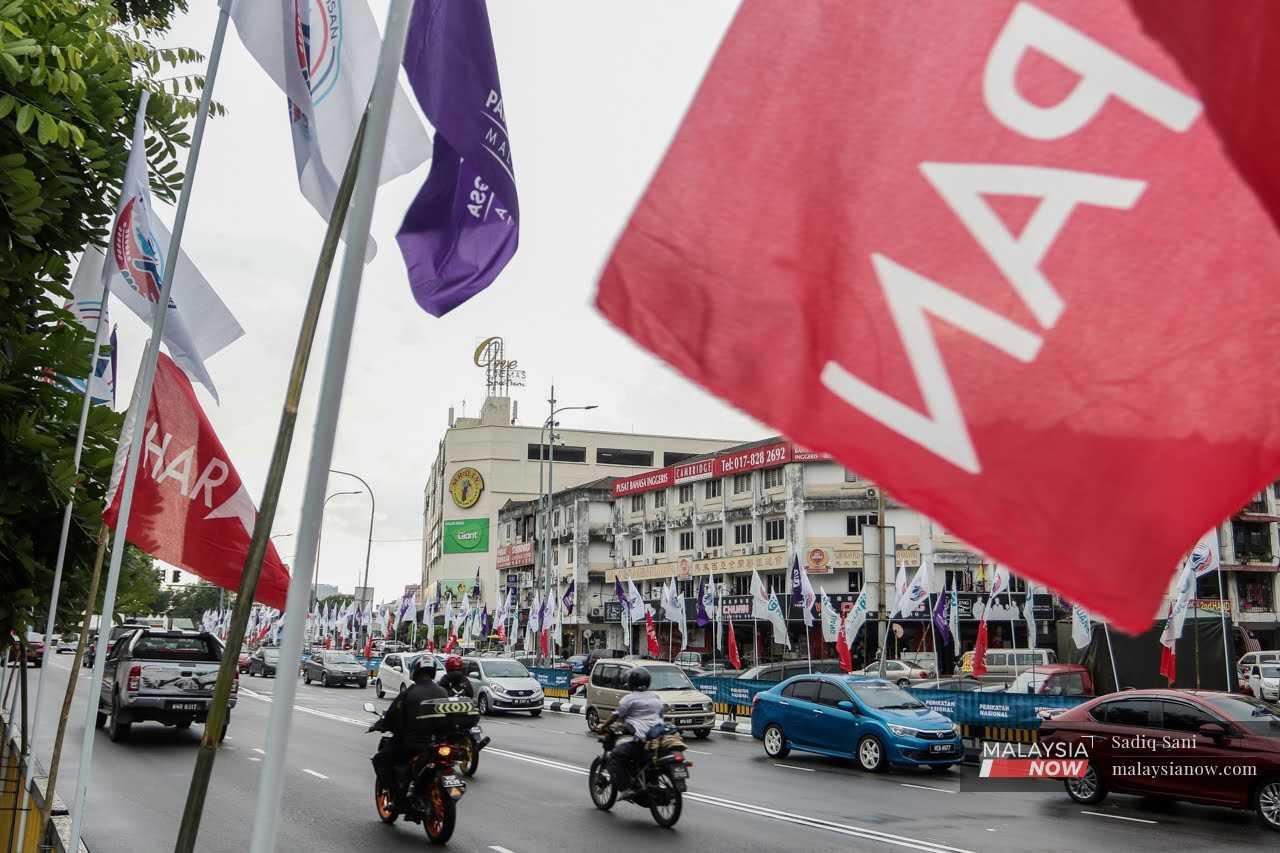 Vehicles move to and fro at a road in Ampang, Selangor, decorated with flags ahead of the 15th general election.  
