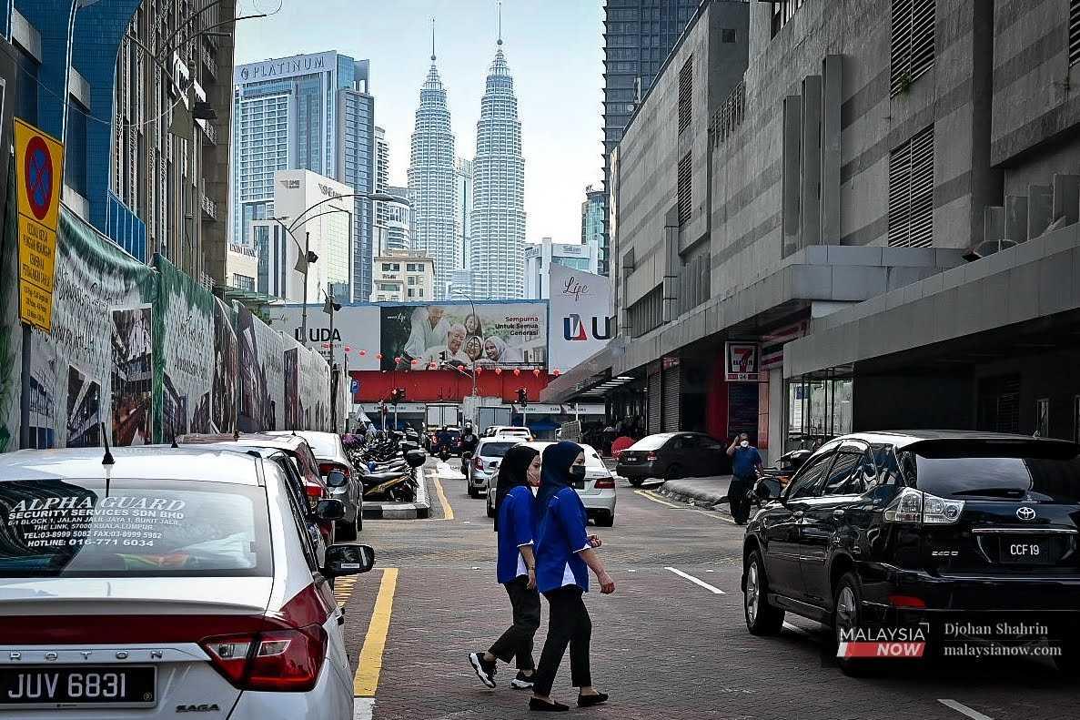 Dua wanita melintasi Jalan Mara, di Kuala Lumpur. Mereka masih memakai pelitup muka sebagai langkah berjaga-jaga dari ancaman Covid-19.