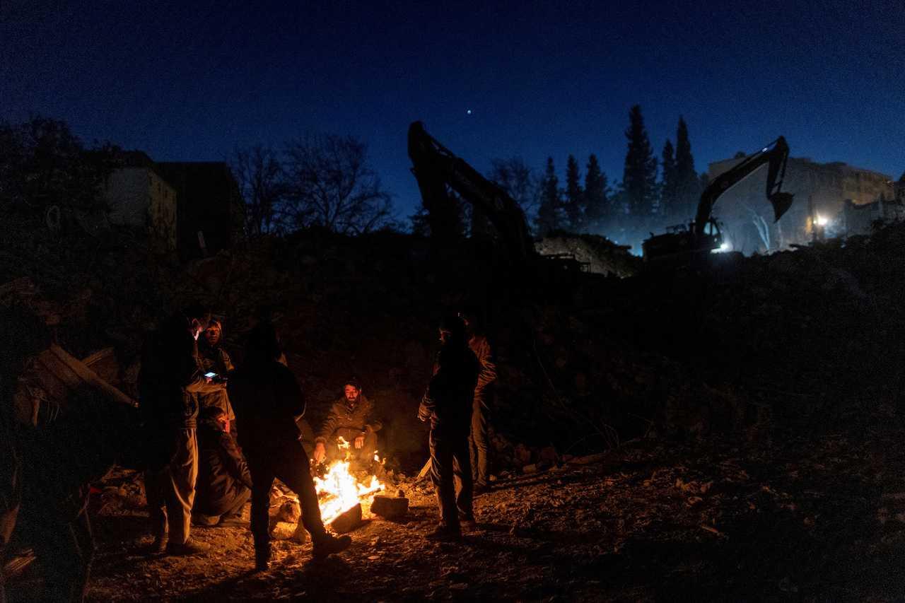 People gather around a fire for warmth as they wait for search and rescue teams to find their missing relatives, following the deadly earthquake in Kahramanmaras, Turkey, Feb 16. Photo: Reuters