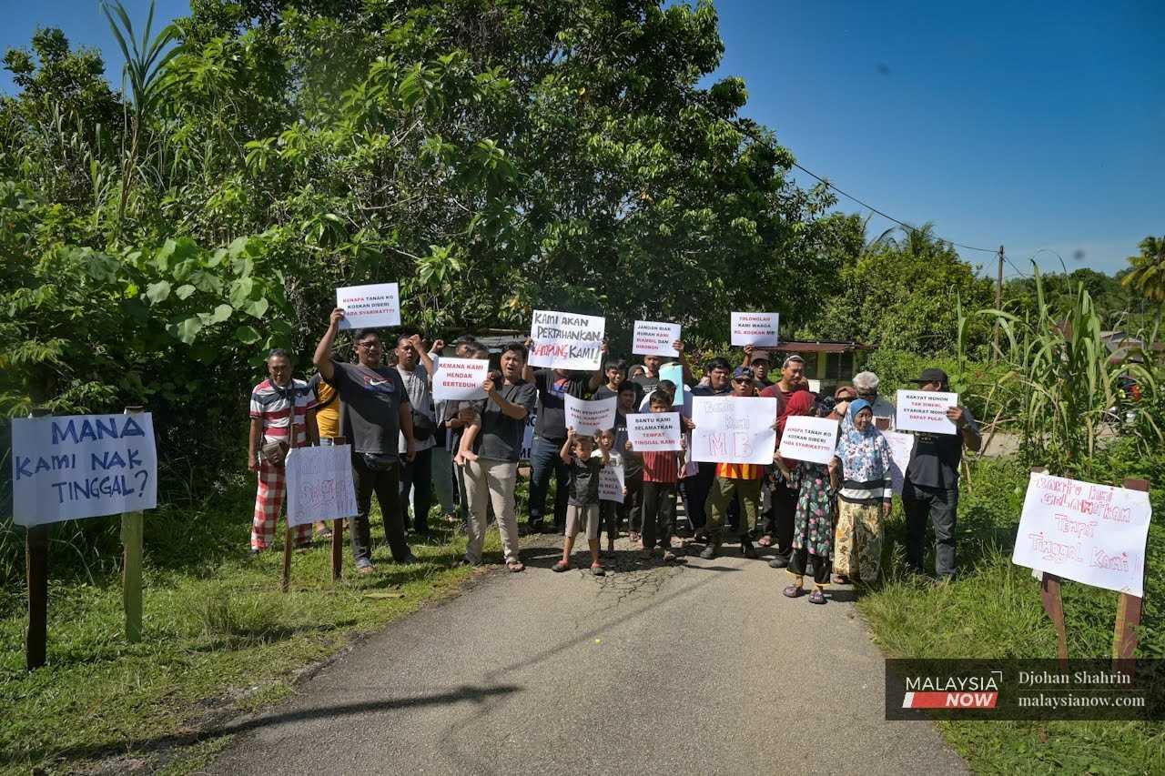 Disgruntled villagers of Kampung Koskan Tambahan holding placards and signs in protest against the acquisition of their land this morning in Rawang.