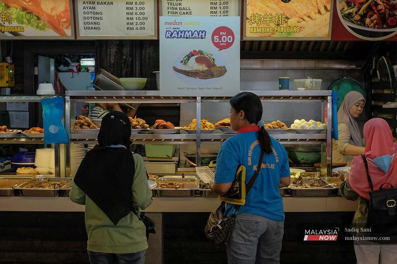 Customers buy lunch at an eatery that serves Menu Rahmah dishes, in Subang, Selangor. 
