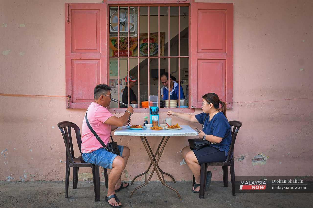 A couple enjoy a quieter breakfast away from the crowds in Kuala Kubu town.