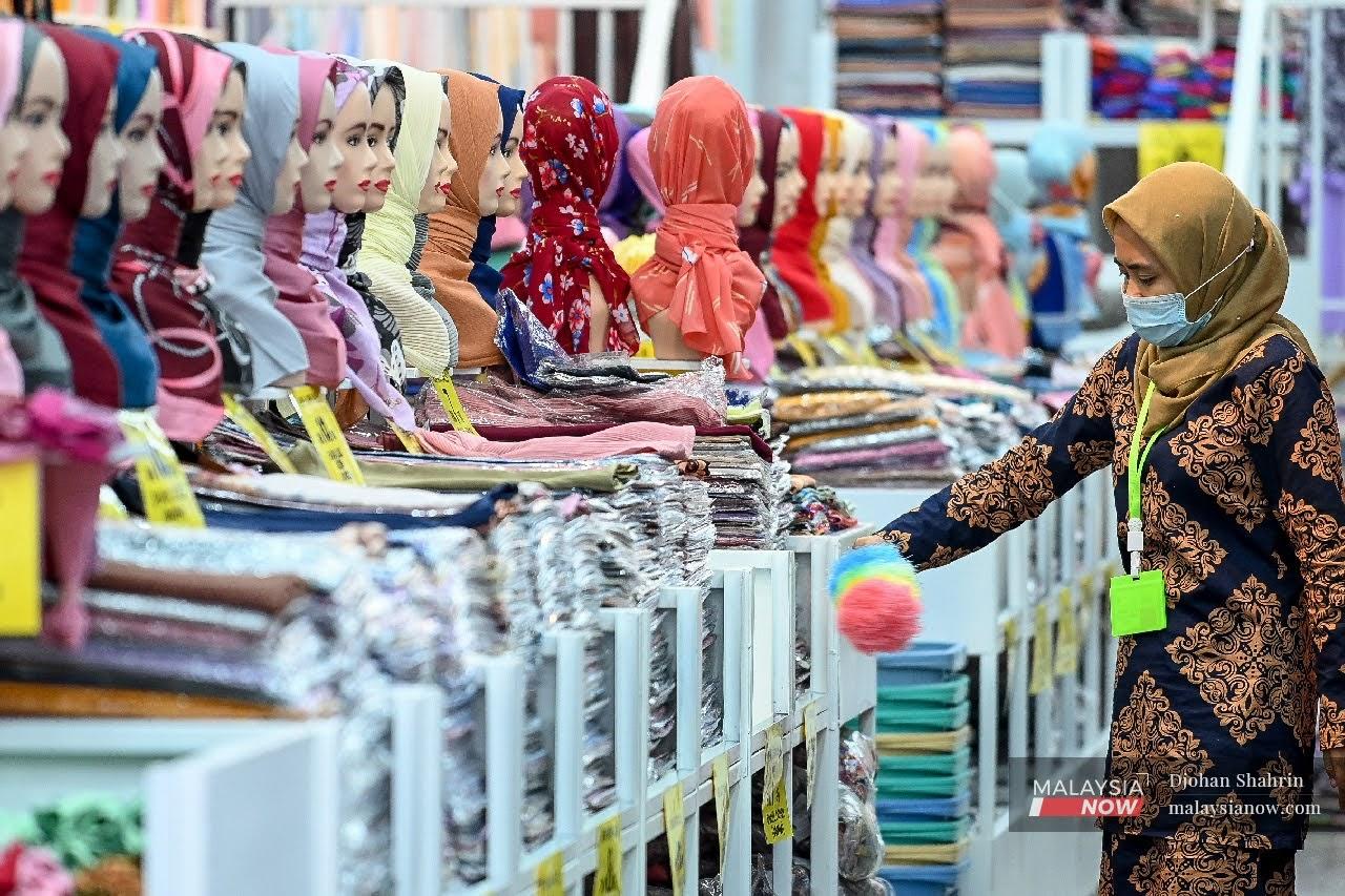 Seorang pekerja sebuah kedai menjual tudung di Jalan Tuanku Abdul Rahman, Kuala Lumpur mematuhi SOP dengan memakai pelitup muka.