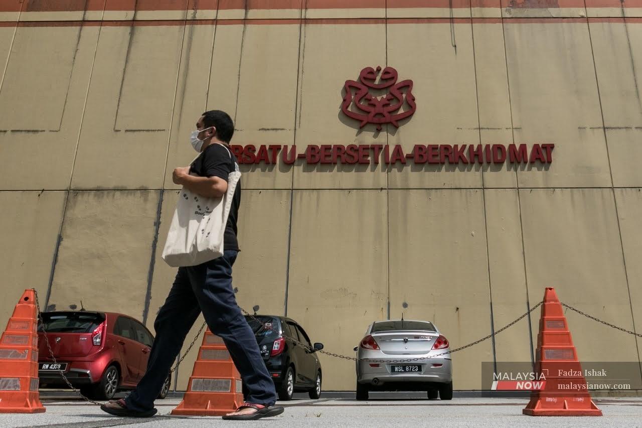 A random man walks infront of UMNO logo at UMNO HQ building in Kuala Lumpur.