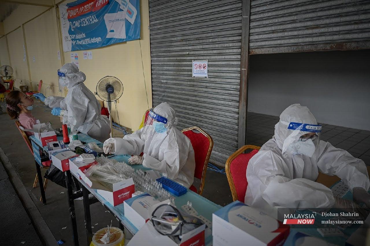 Health workers collect swab samples for testing at a Covid-19 screening at USCI's Laurent Bleu clinic in Taman Connaught, Cheras.