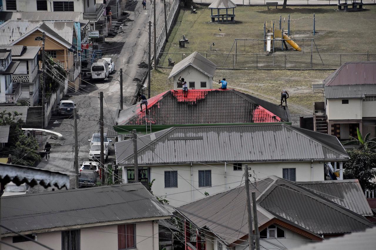 People clean volcanic ash from the red roof of a home after La Soufriere volcano erupted, in Wallilabou, on the western side of the Caribbean island of St Vincent, April 12. Photo: AP
