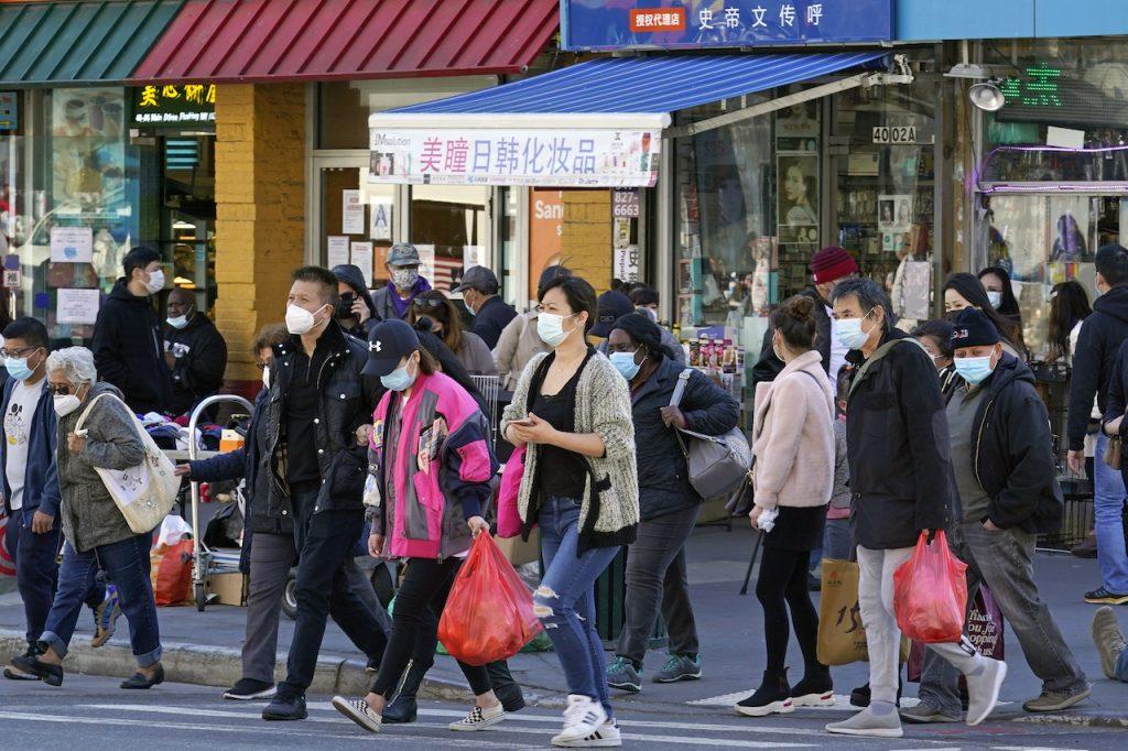 People cross a busy street in the shopping district of Flushing, a largely Asian American neighbourhood in the Queens borough of New York, March 30. A rash of anti-Asian attacks across the US has led police and others to step up patrols in neighborhoods like this one. Photo: AP