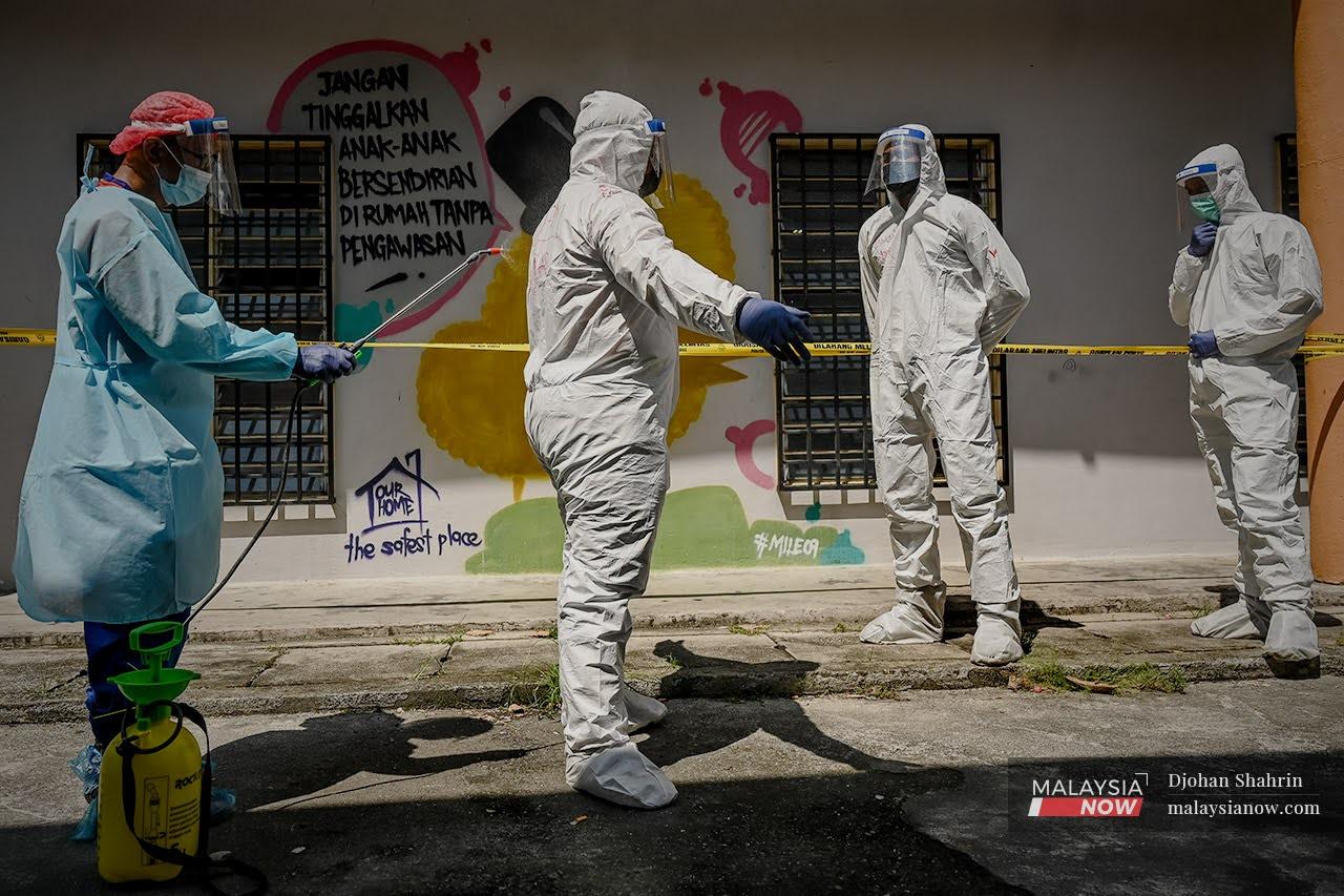 Members of the Civil Defence Force are sprayed with sanitiser after entering the Sri Penara flats area in Cheras, Kuala Lumpur. The area was placed under enhanced movement control order following the detection of over 100 Covid-19 cases during a community screening of residents.