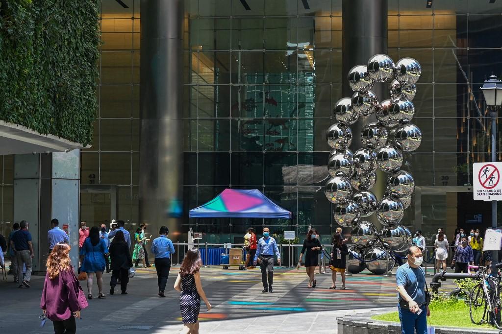 People walk along a promenade at the Raffles Place financial business district in Singapore on April 20. Photo: AFP