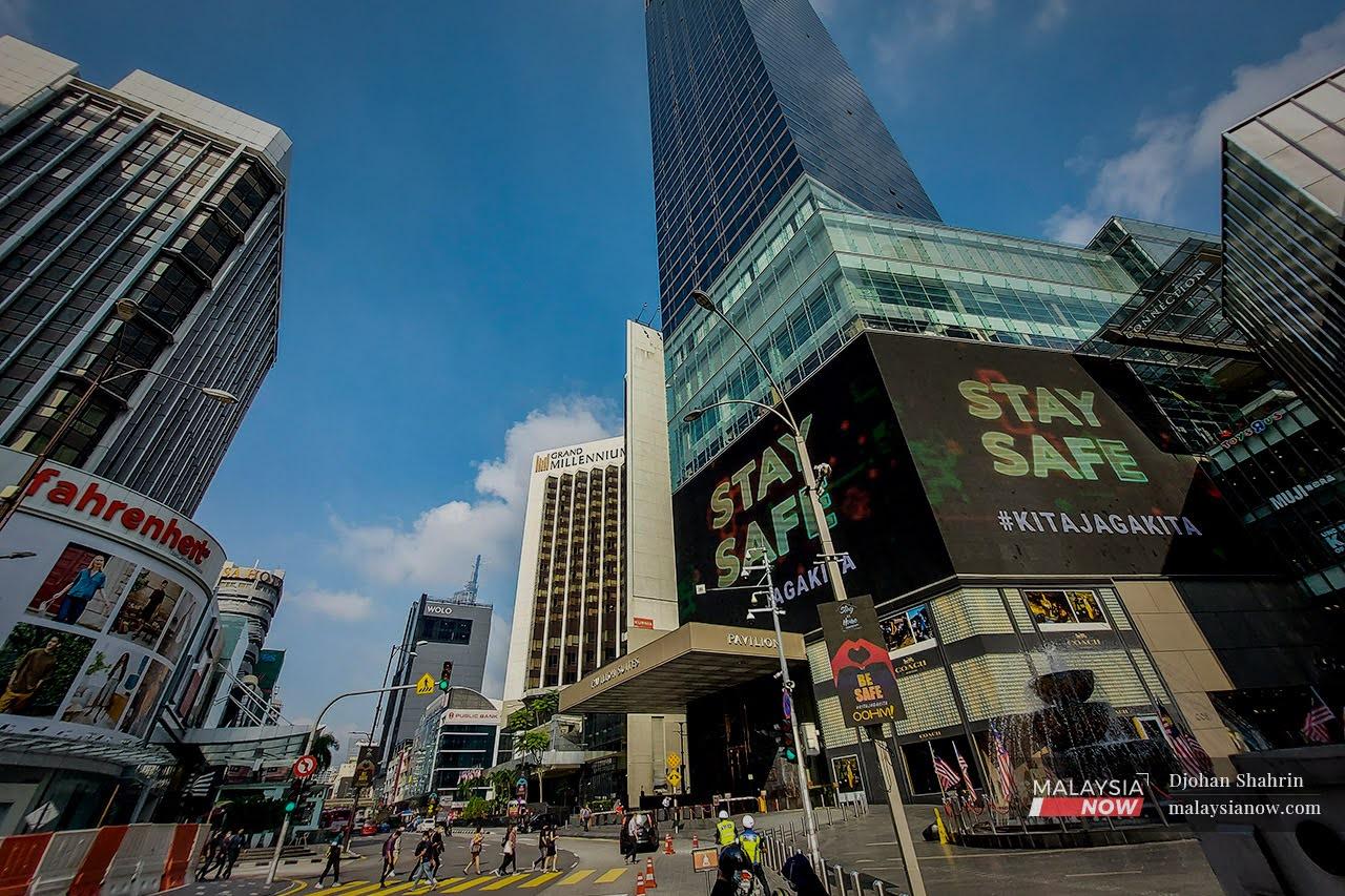 Pedestrians cross a road in Bukit Bintang, Kuala Lumpur, as traffic in the city begins to build up again.