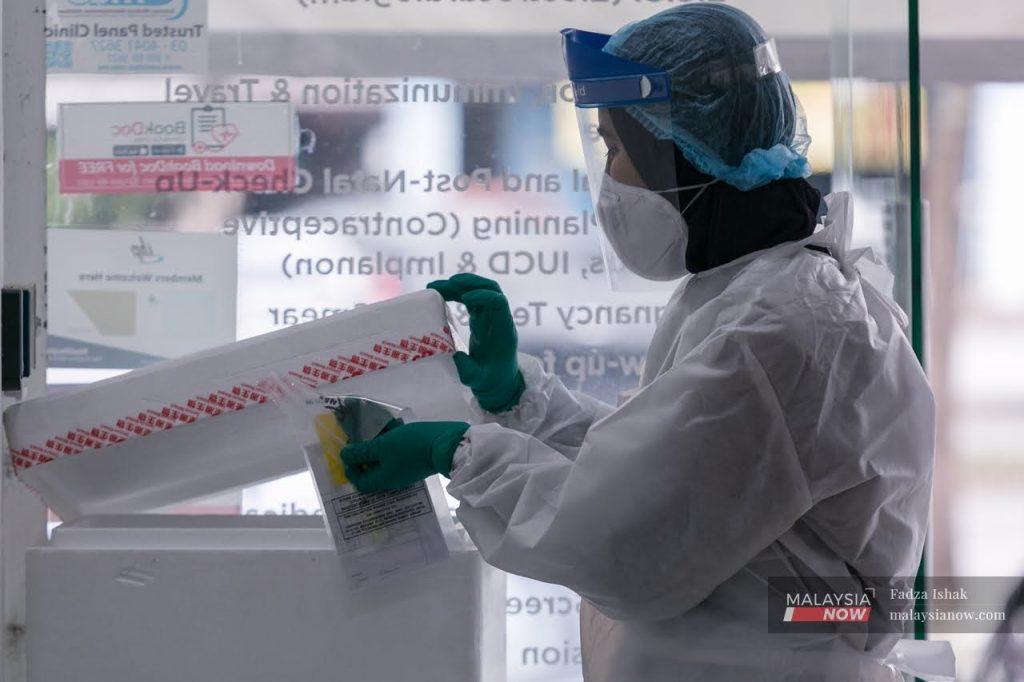 Seorang petugas barisan hadapan meletakkan sampel ujian swab sebelum di hantar ke makmal untuk diuji.