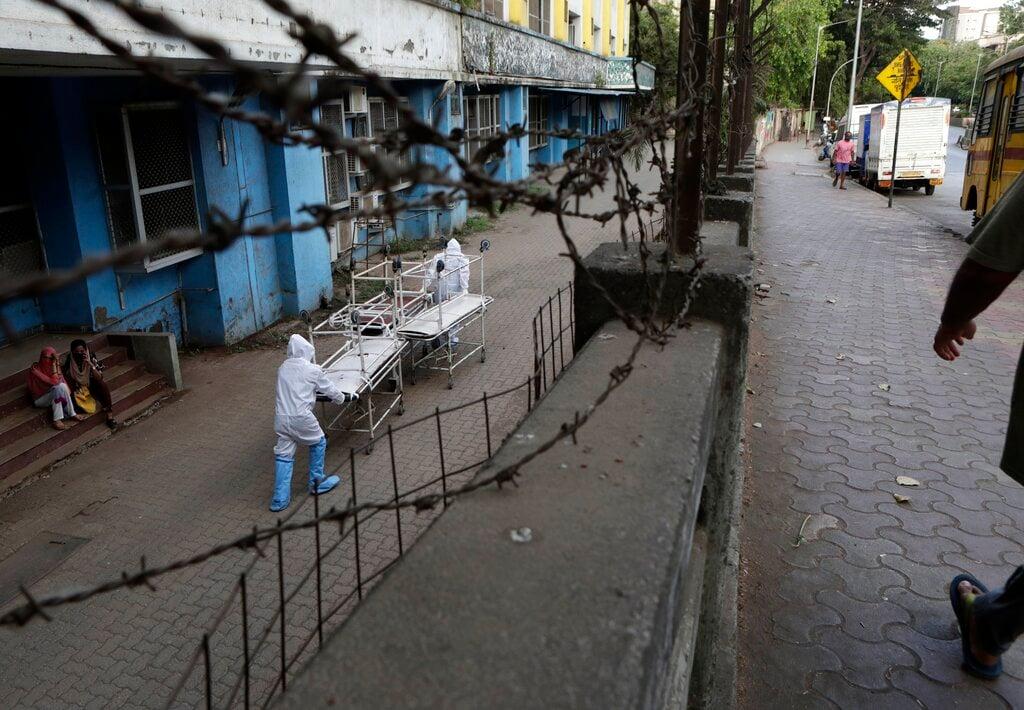 Hospital staff dressed in protective gear carry empty stretchers from a morgue towards a hospital in Mumbai, India, in this May 29, 2020 file photo. Photo: AP
