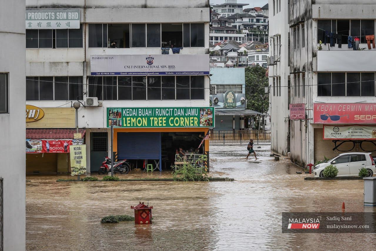 A man walks through flood waters at a town in Balakong, Selangor.