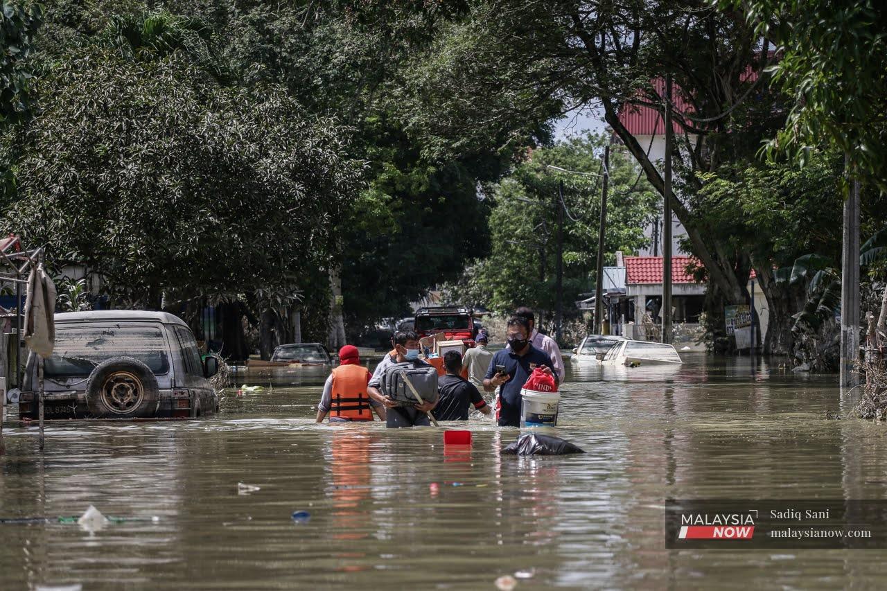 Flood victims in Taman Sri Muda, Shah Alam, make their way through waist-high water to collect food and supplies from the nearest relief centre.
