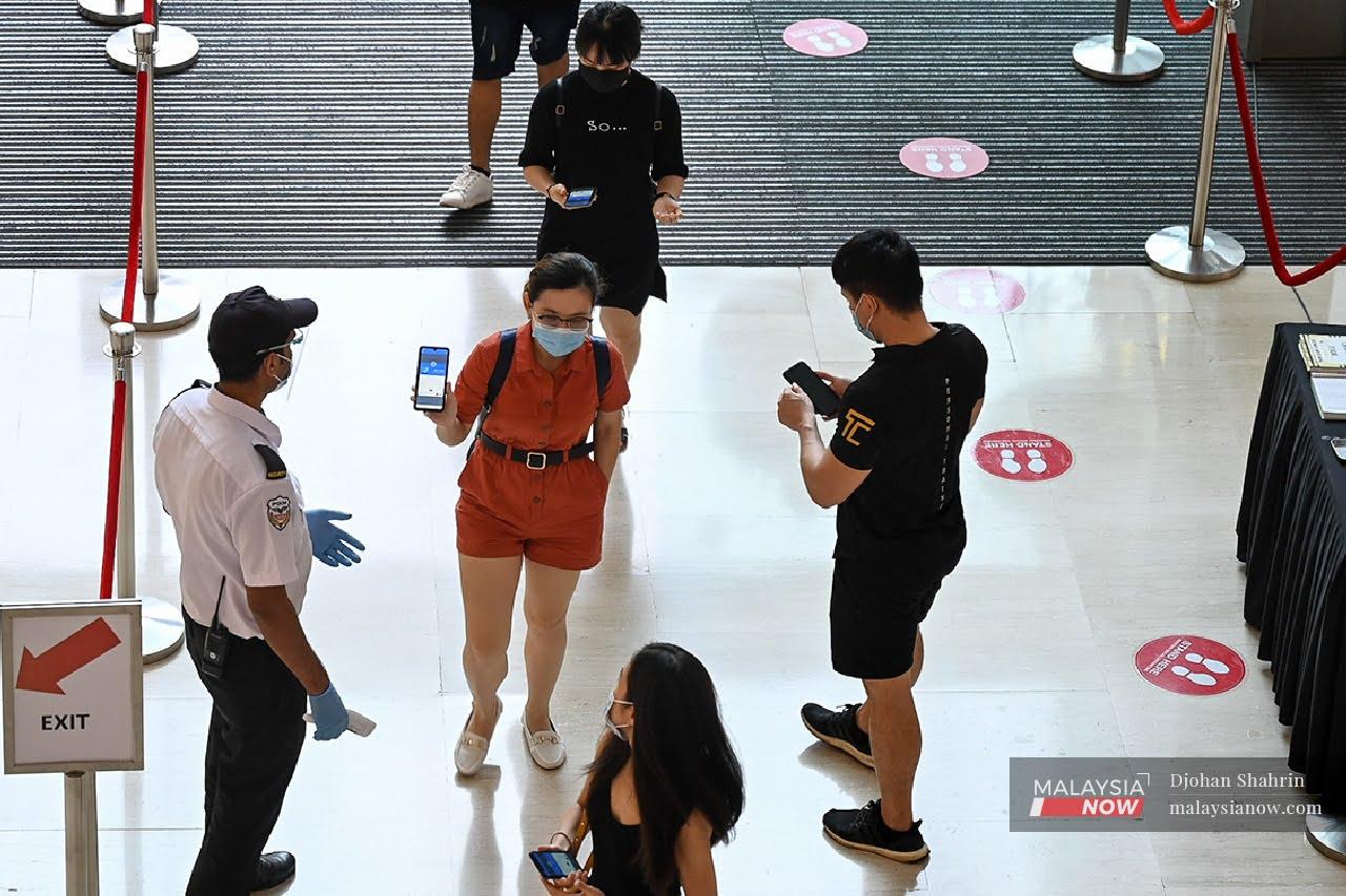 Orang ramai perlu menunjukkan aplikasi MySejahtera kepada pengawal keselamatan sebelum masuk ke kompleks membeli belah bagi mengelak penularan virus Covid-19.