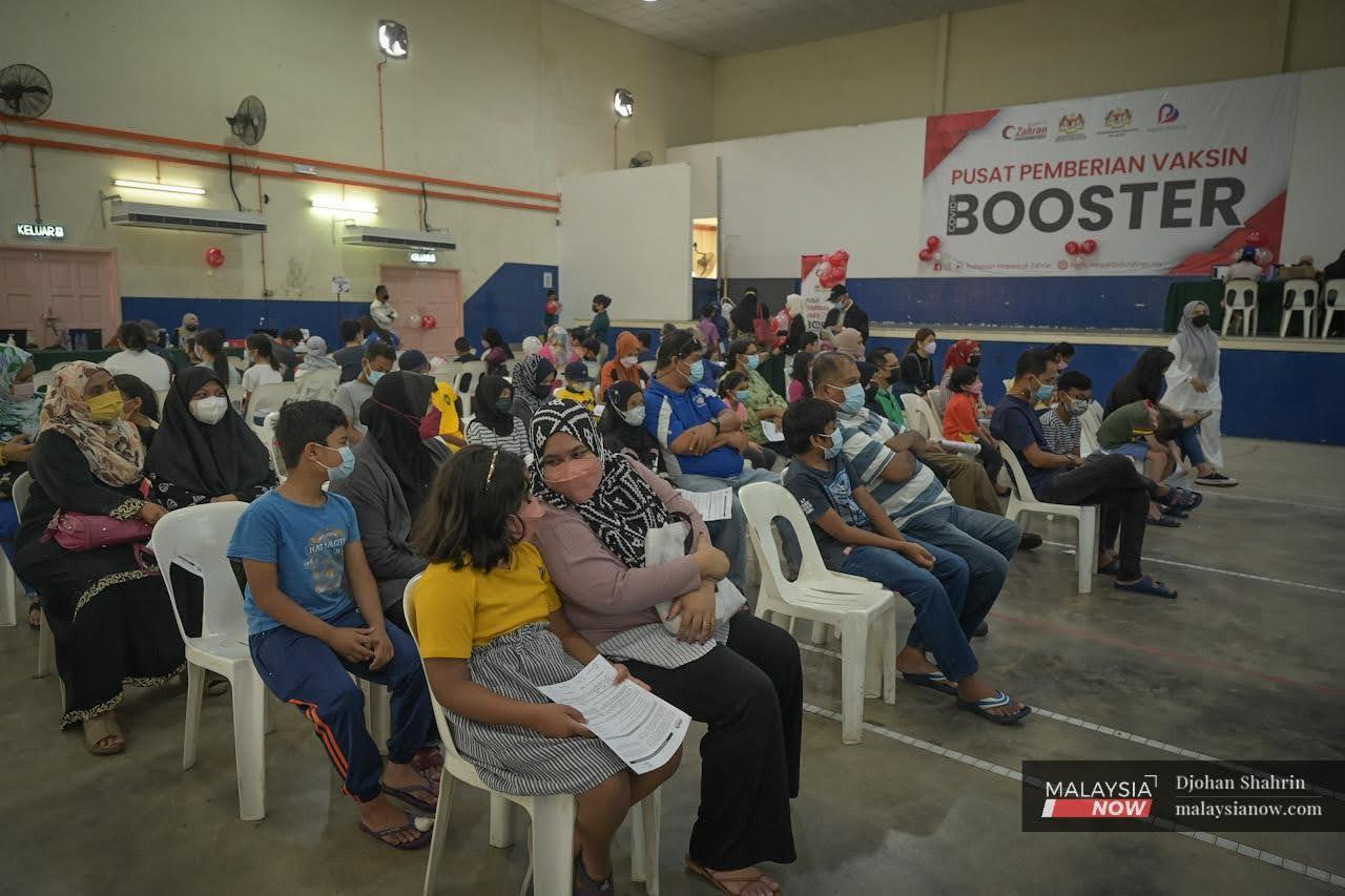 Parents wait with their children at a vaccination centre providing booster shots as well as vaccine jabs for kids at the Dewan Komuniti Taman Bukit Mewah in Kajang.