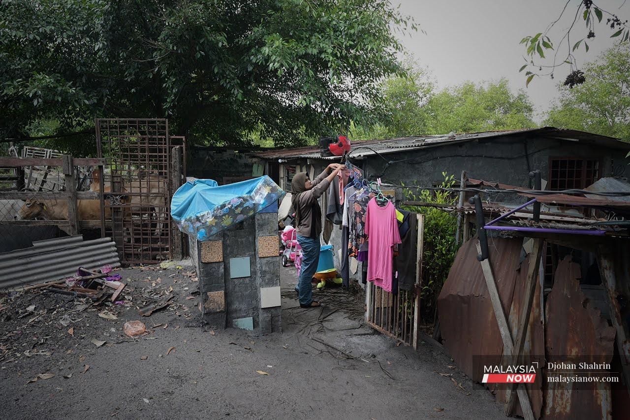 Zarifah Ahamad hangs the family's laundry out to dry in front of their tiny house in the fishing village of Kampung Teluk Muroh in Lumut, Perak.