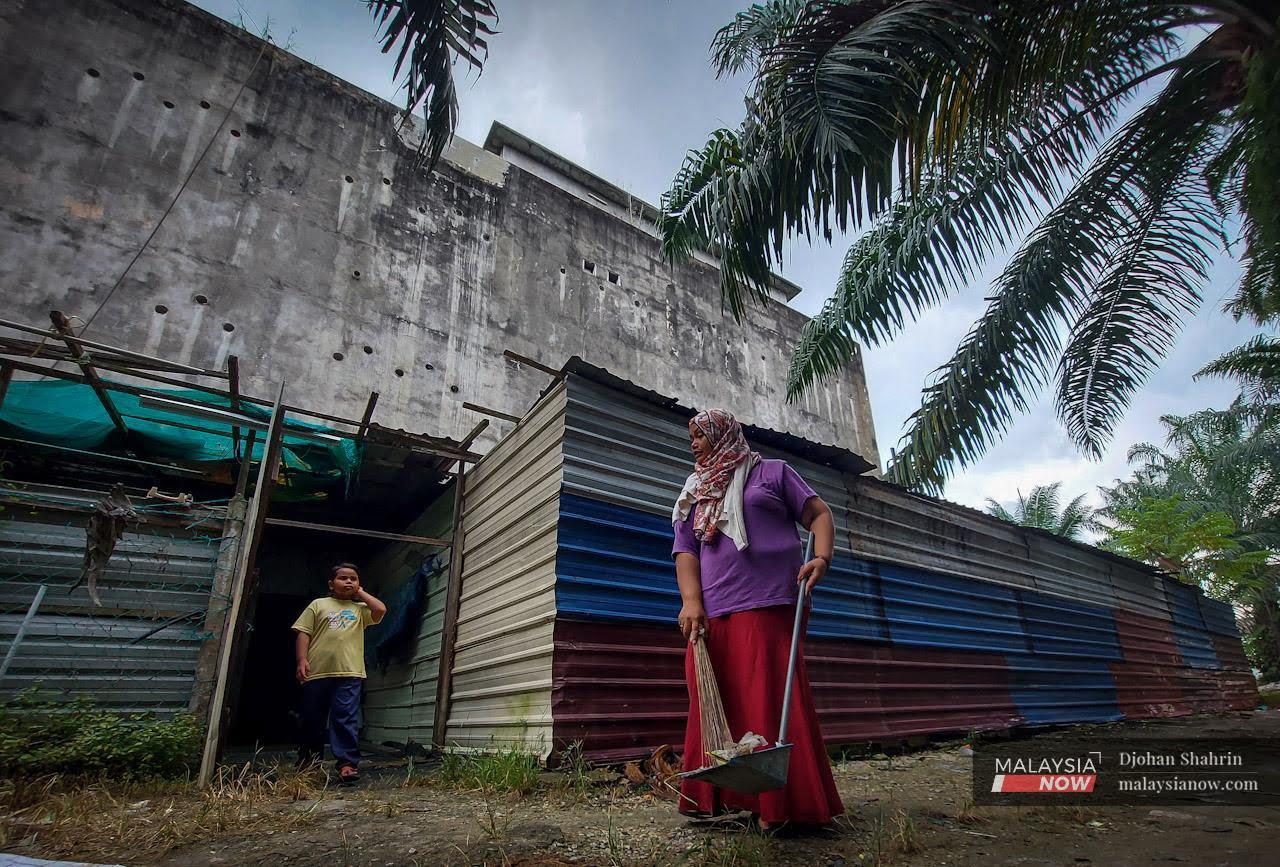 Hamidah sweeps the ground outside her home in a concrete building used for the farming of swiftlets, in Sitiawan, Perak.