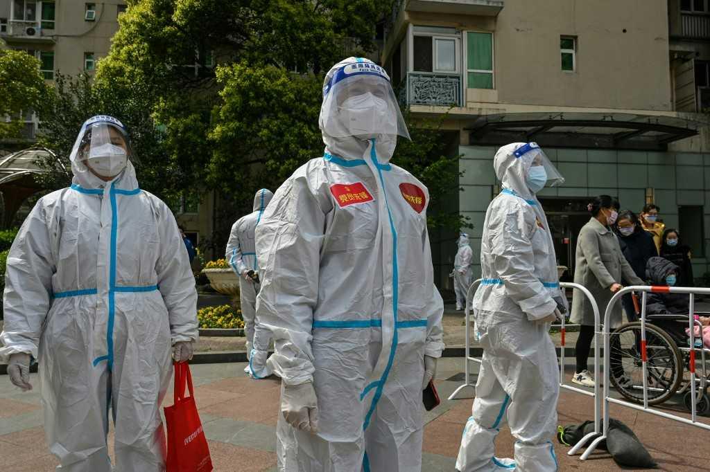 Workers and volunteers look on in a compound where residents are tested for Covid-19 during the second stage of a pandemic lockdown in Jing'an district in Shanghai on April 1. Photo: AFP