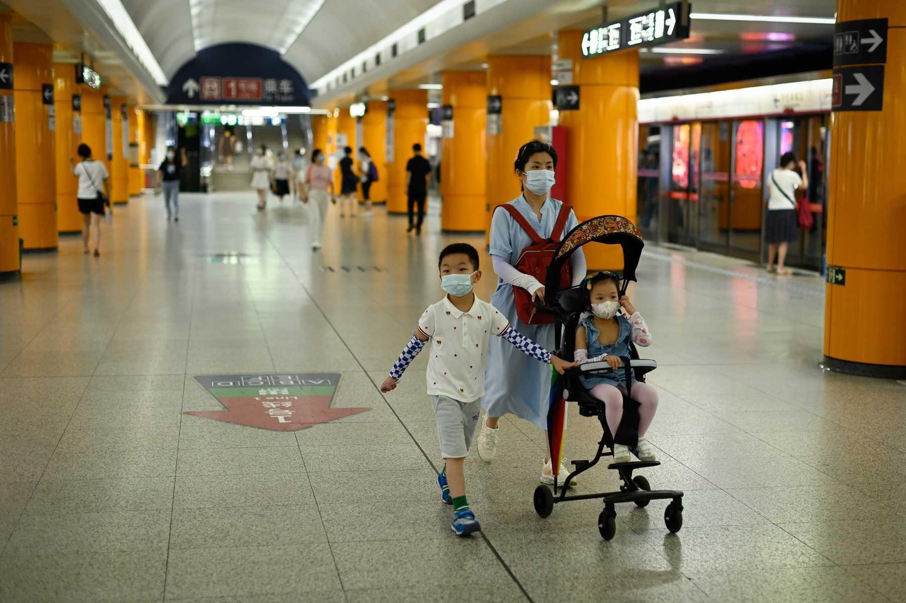 A woman walks in a subway station with two children in Beijing on July 5. Photo: AFP