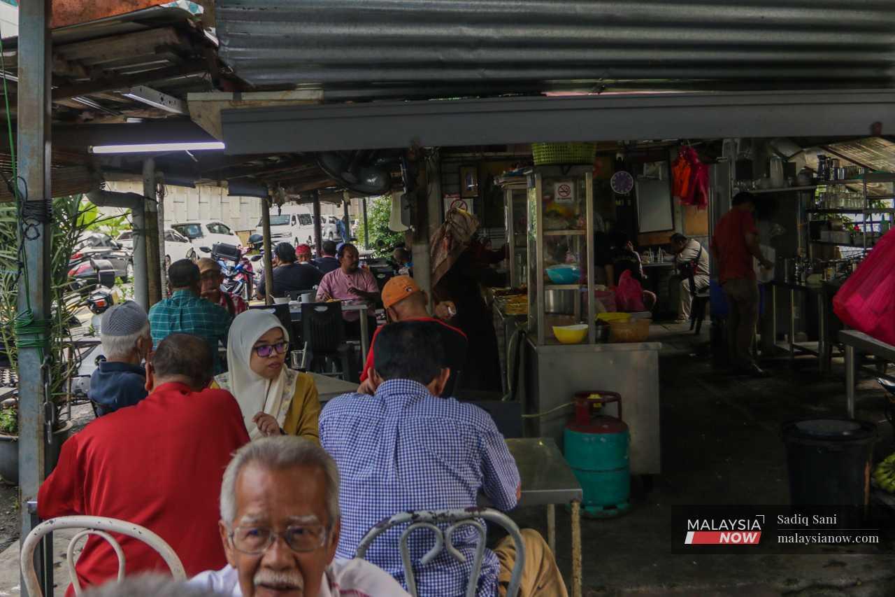 Pelanggan sebuah warung menikmati hidangan di Kampung Sungai Baru yang menjadi tumpuan pekerja pejabat dan penduduk tempatan.