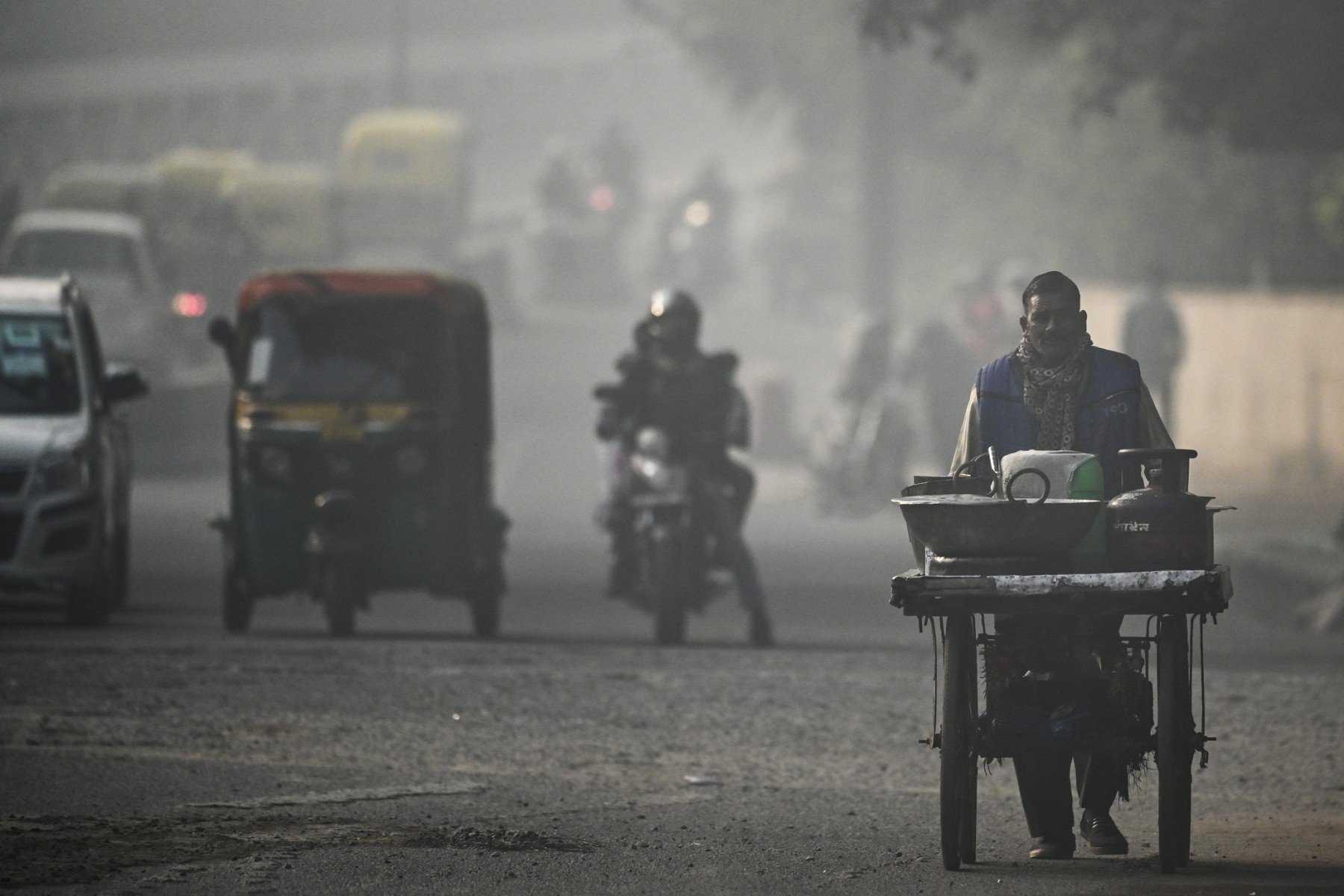 A street food vendor pushes his cart along a road amid smoggy conditions in New Delhi on Dec 23, 2021. Photo: AFP