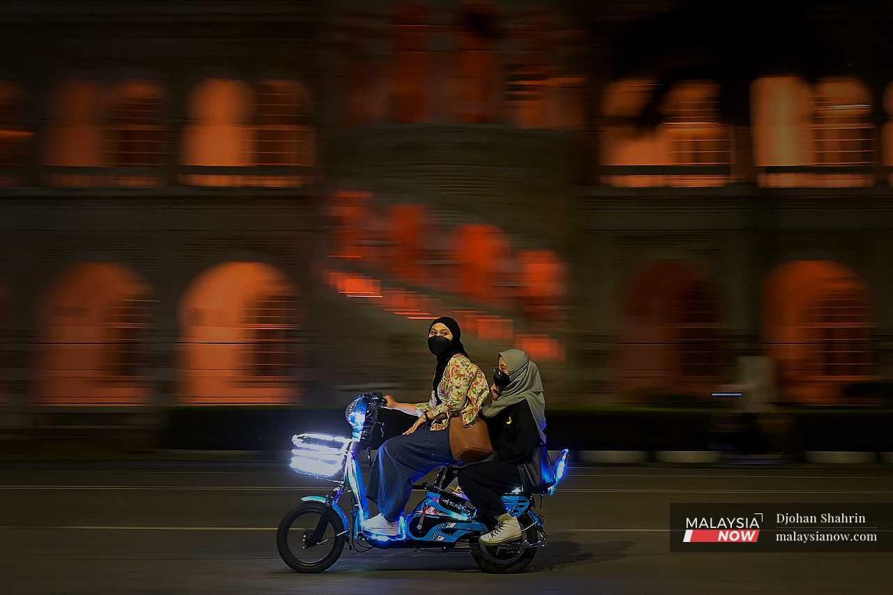 Dua wanita bersiar-siar dengan skuter mini elektrik di hadapan bangunan Sultan Abdul Samad.