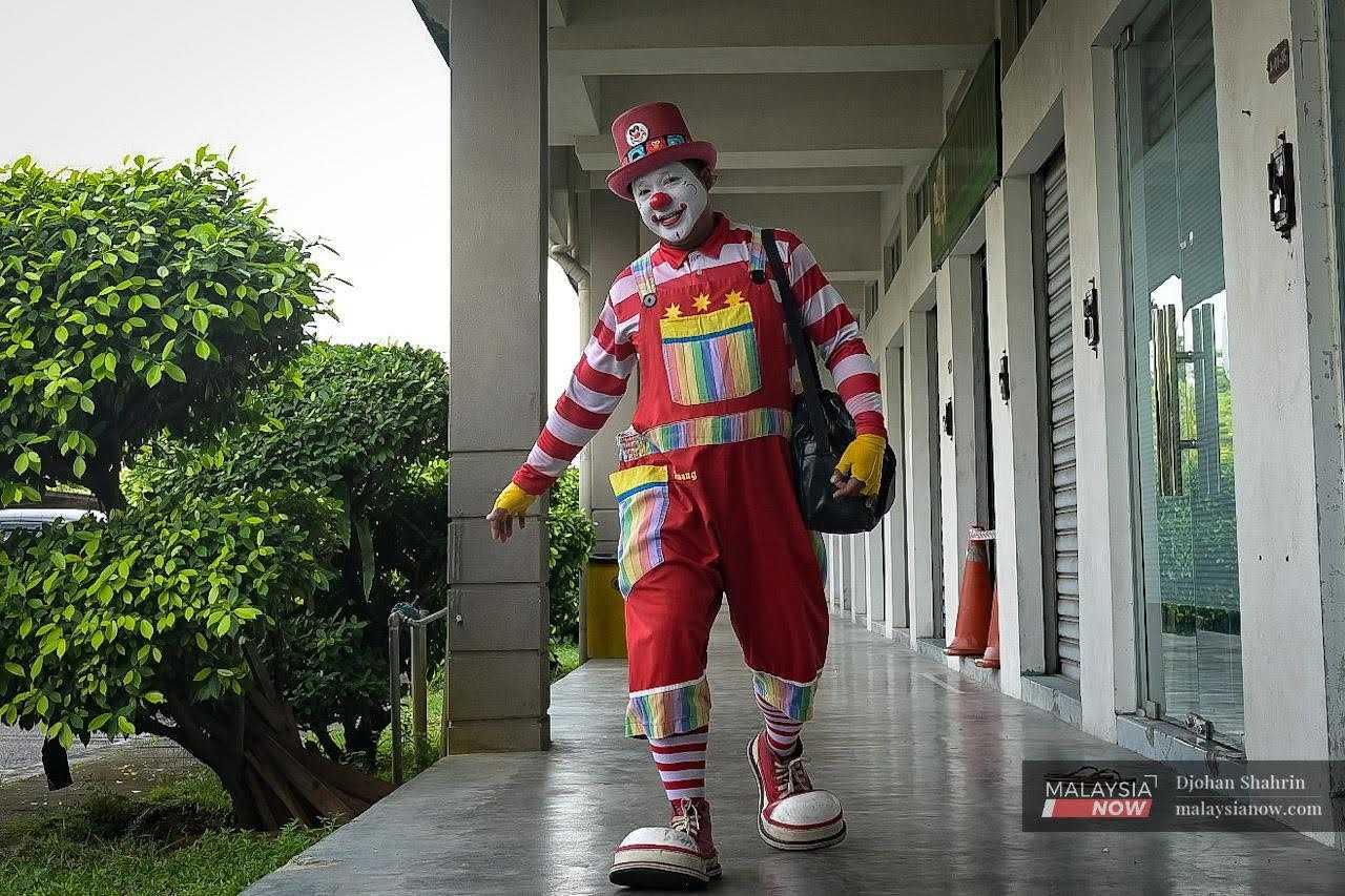 Walking along a row of shoplots, Awang the Clown brings a smile to the face of everyone who sees him. 
