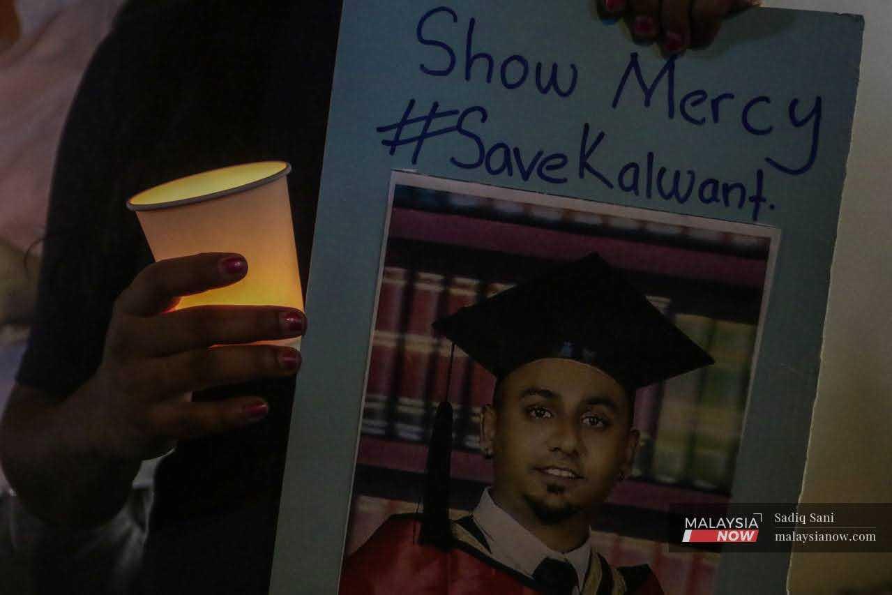 A woman holds a picture of Kalwant Singh, a Malaysian on death row in Singapore who is scheduled to be executed tomorrow morning, at a candlelight vigil outside the Singapore High Commission in Jalan Ampang, Kuala Lumpur.