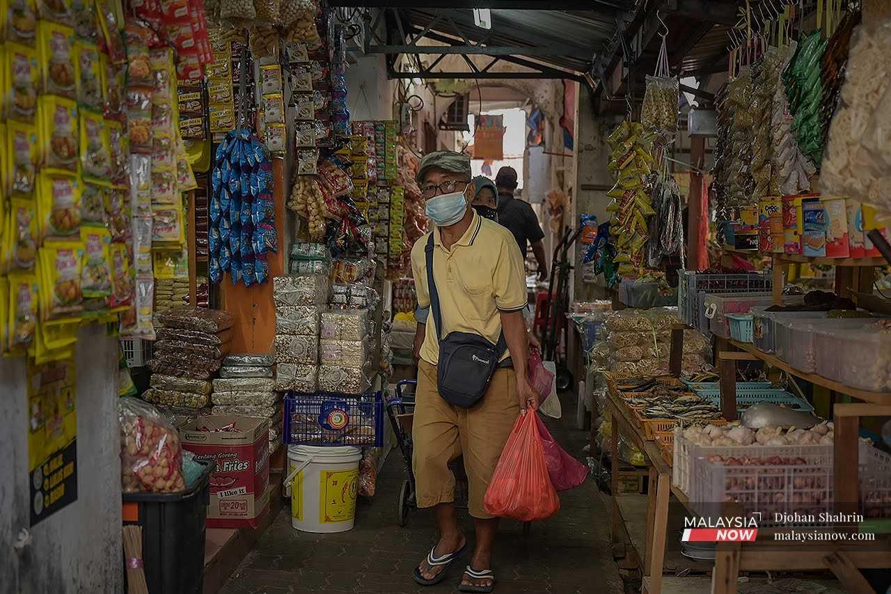 Seorang pelanggan memakai pelitup muka ketika membeli barang di Pasar Chow Kit, Kuala Lumpur bagi mengelak jangkitan Covid-19.