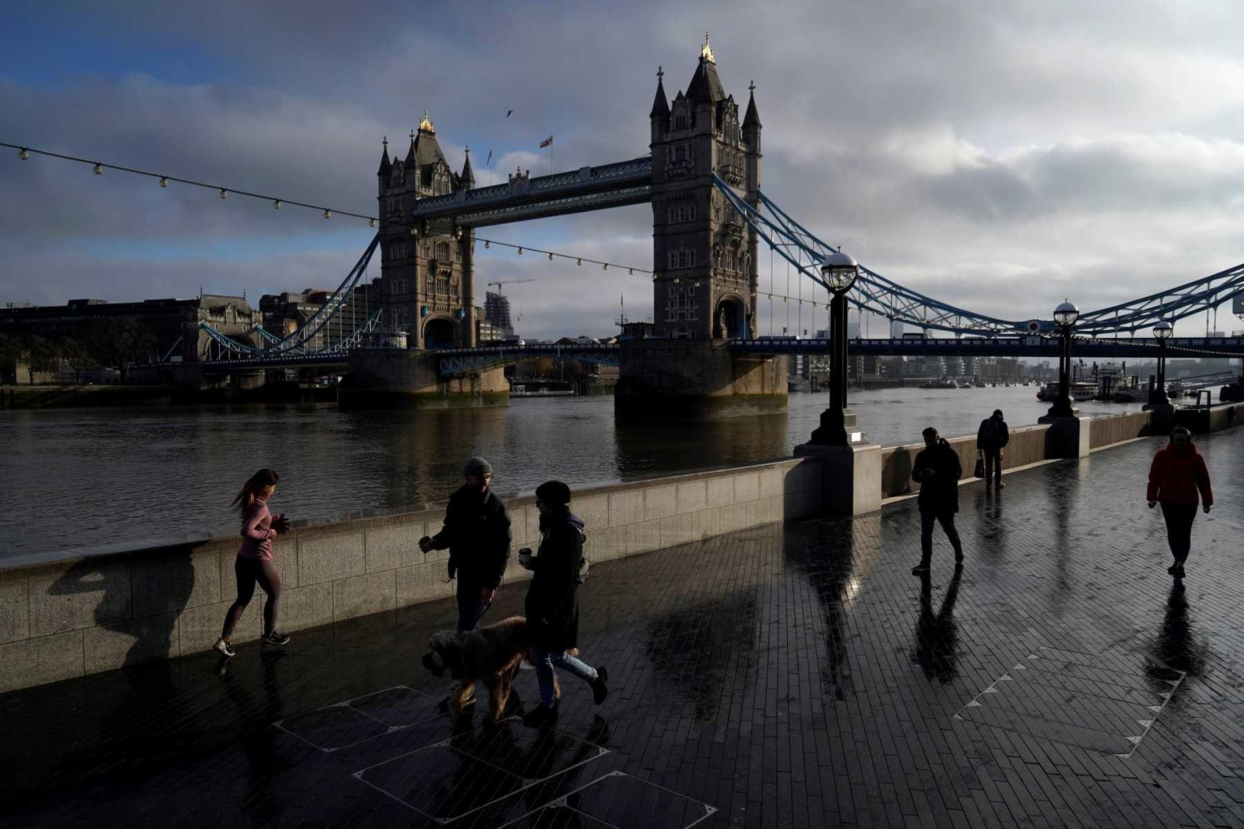 People take their daily exercise along the Thames river embankment near the Tower Bridge in central London on Feb 4, 2021, during the third national lockdown. British Airways have been among the worst affected by sector-wide turmoil, as carriers race to meet soaring demand after the lifting of Covid travel restrictions. Photo: AFP