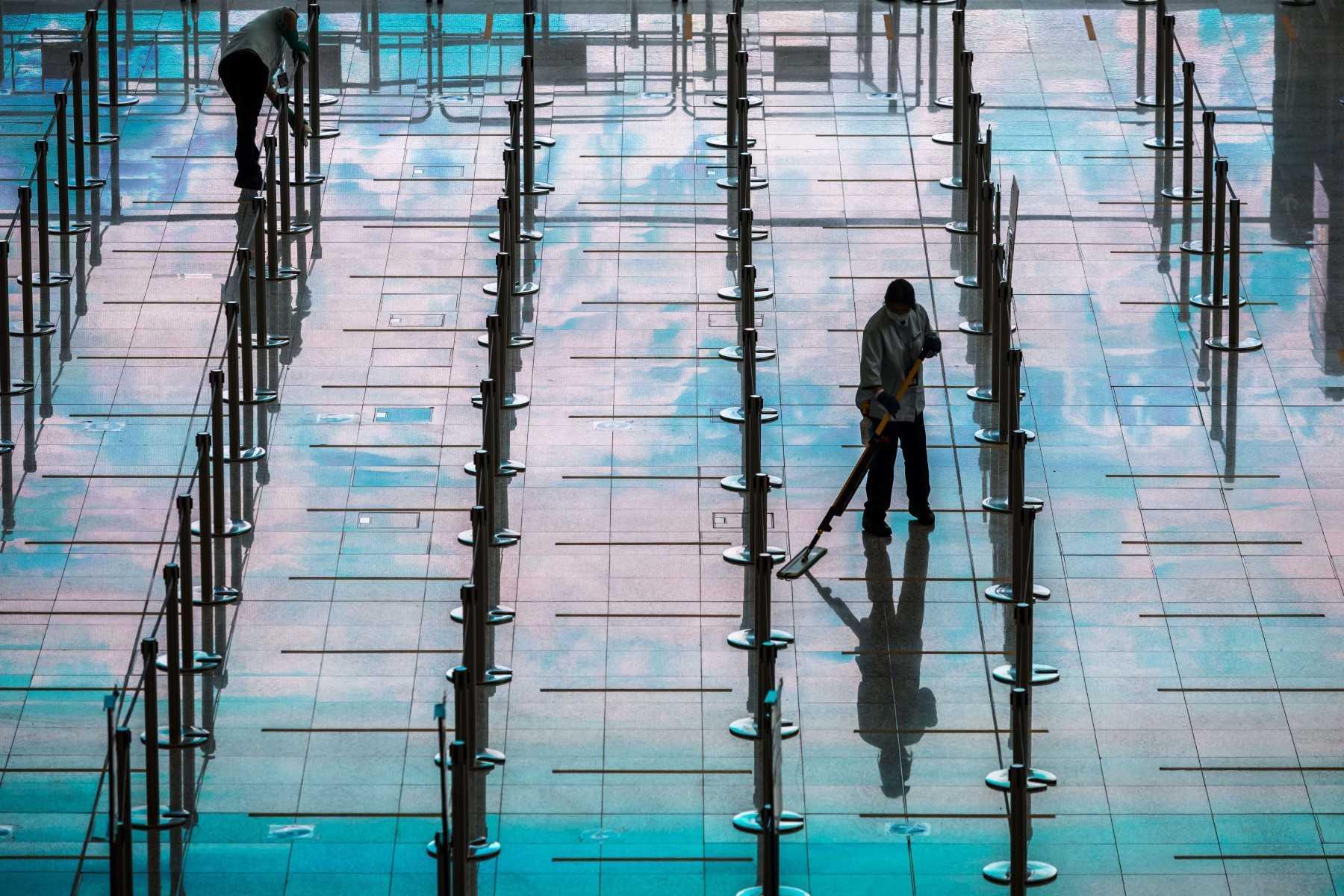 Workers clean an area for arriving passengers before they board buses to their quarantine hotels amid the Covid-19 pandemic, at Hong Kong International Airport in Hong Kong on March 21. Photo: AFP