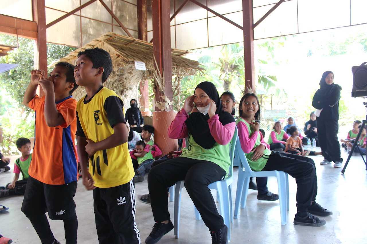 Orang Asli children play an educational version of musical chairs with students from Universiti Teknologi Mara.
