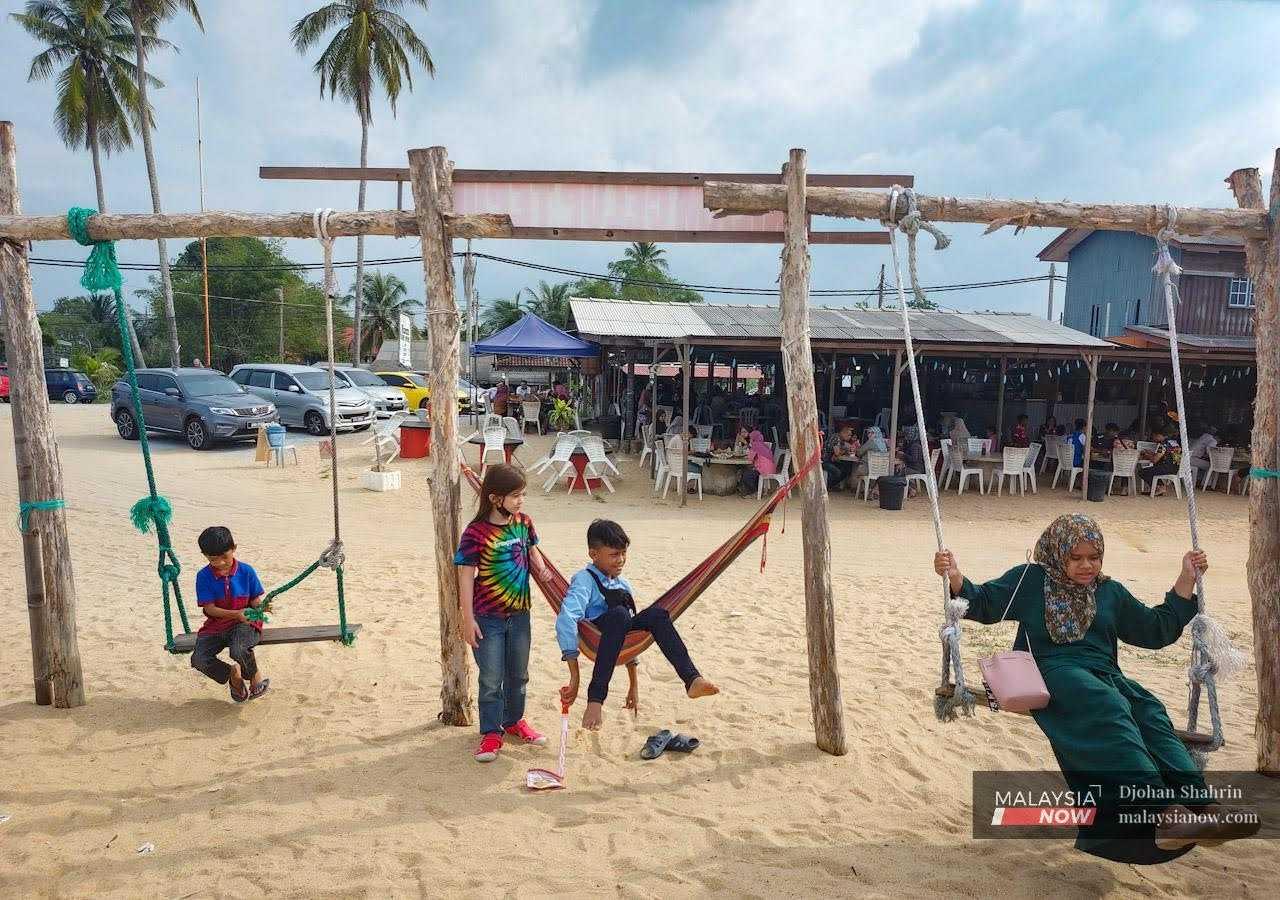 Kanak-kanak bermain buaian di pantai Kampung Mengkabang Telipot, Kuala Terengganu. Pelitup muka bagi mengelak jangkitan Covid-19 tidak lagi diwajibkan di kawasan terbuka.