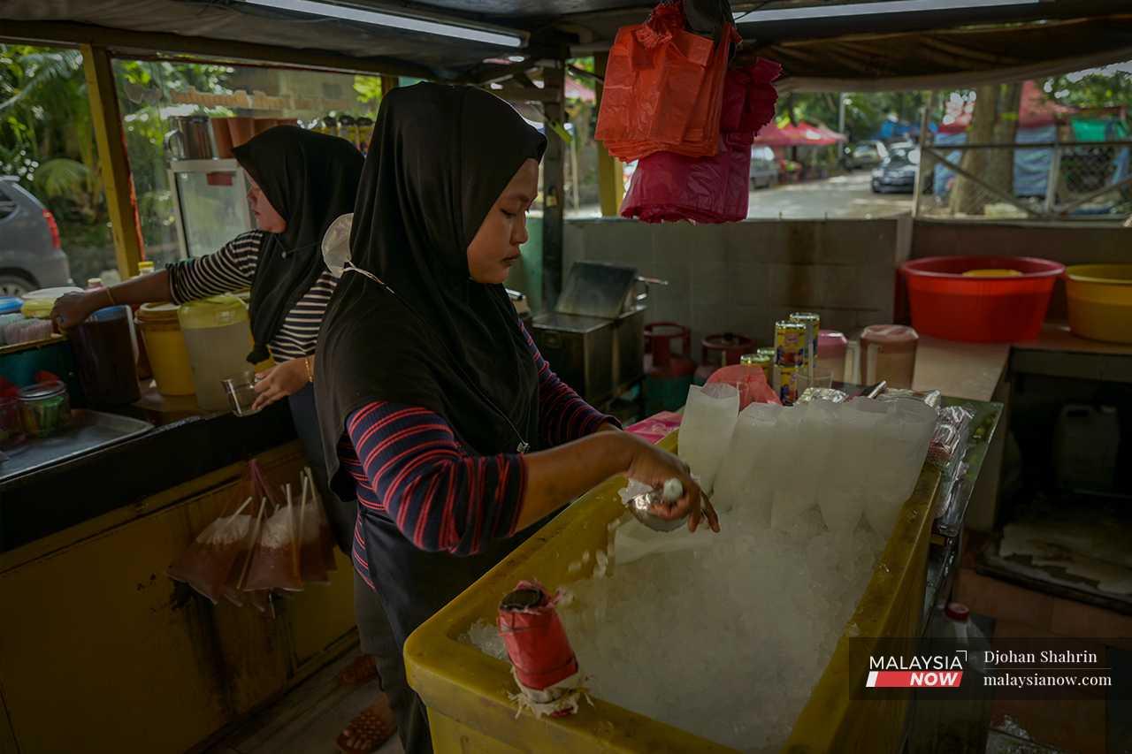 Pekerja Huri menyiapkan pesanan - membancuh minuman dan mengisi ais ke dalam beg plastik yang diikat dengan tali rafia – teknik pembungkusan air yang dikenali sebagai 'ikat tepi'.