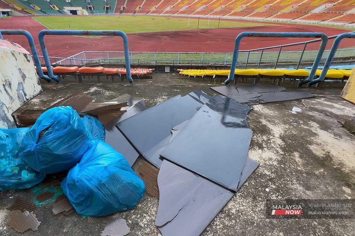 Serpihan atap bumbung stadium dikumpulkan di sebelah beg sampah dan menunggu masa untuk dibuang.
