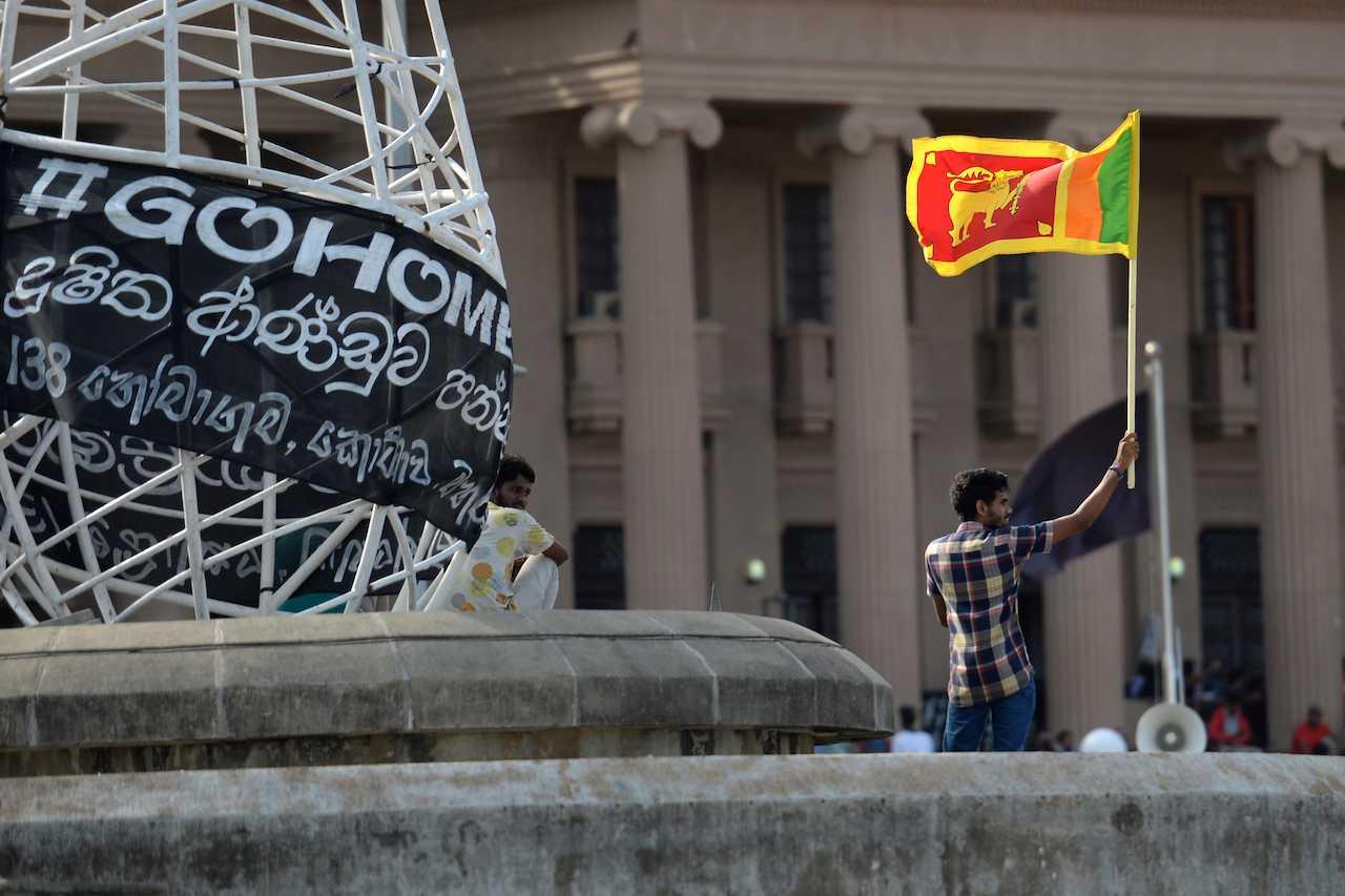 Seorang penunjuka perasaan mengibarkan bendera Sri Lanka di pejabat presiden, Colombo pada 13 Julai lalu. Gambar: AFP