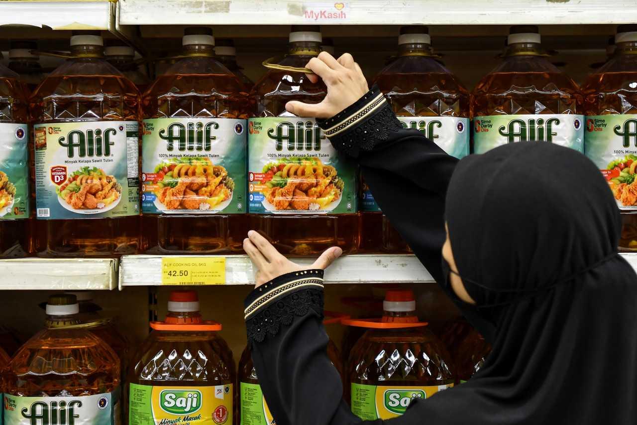 Seorang pekerja menyusun minyak masak di rak sebuah pasar raya di Kuala Terengganu. Gambar: Bernama