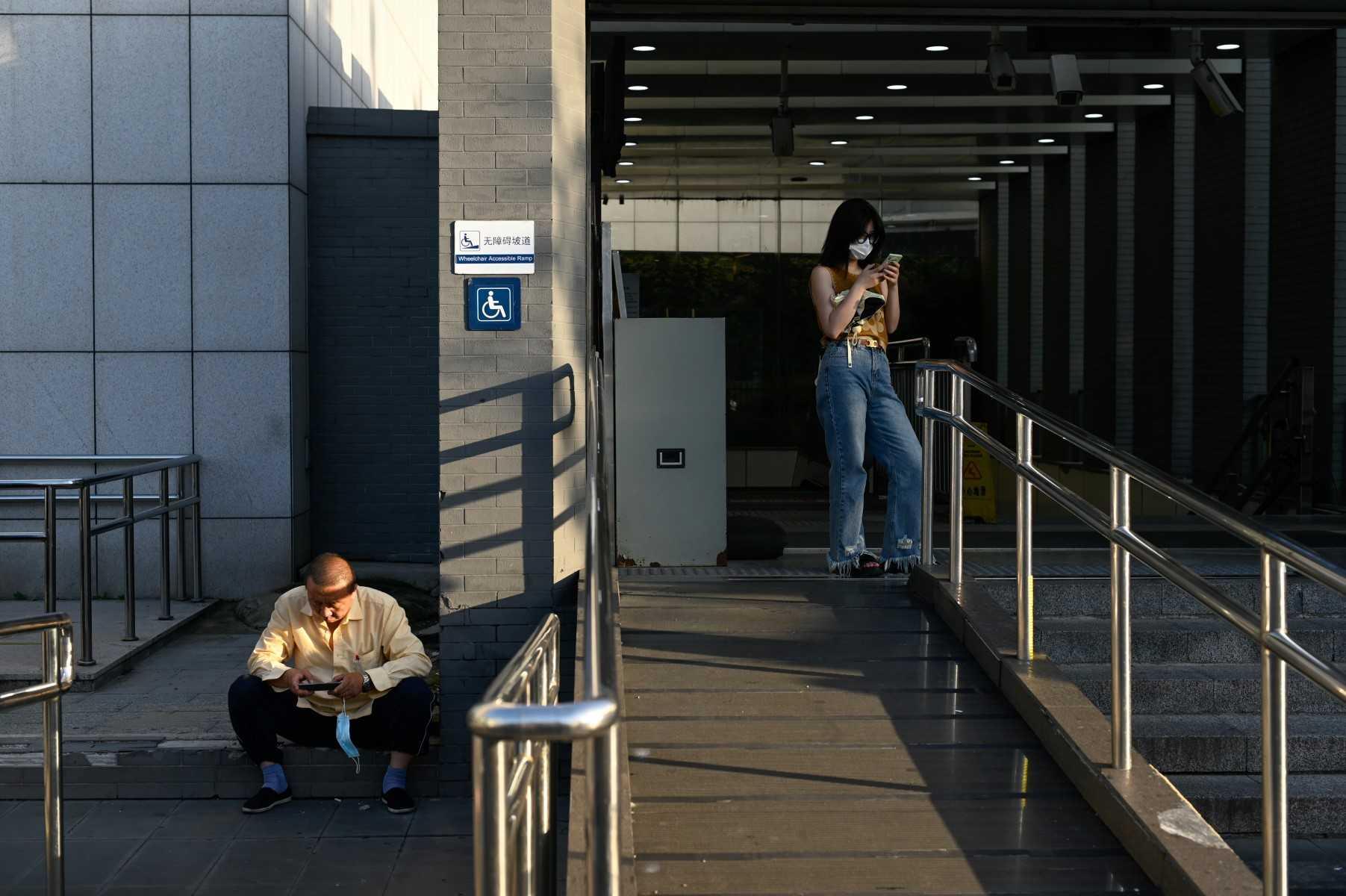 People use their mobile phones at the entrance of a subway station in Beijing on July 13. Photo: AFP 