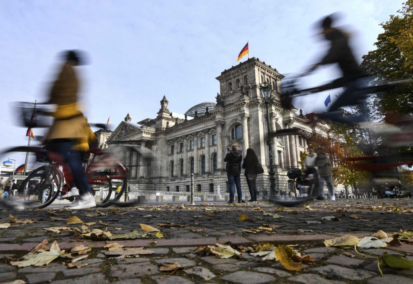 Leaves lie on the ground as pedestrians and bicycle riders are seen in front of the Reichstag building housing the lower house of parliament Bundestag in Berlin, Germany, on Oct 19, 2021. Photo: AFP
