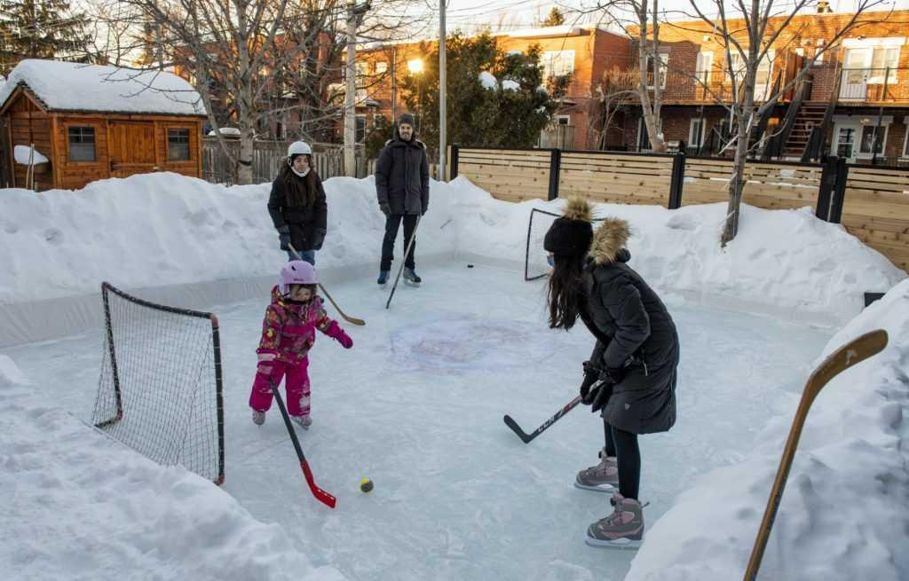 A man and his family play hockey on the ice rink in their backyard in Montreal, Quebec on Feb 10. Photo: AFP 