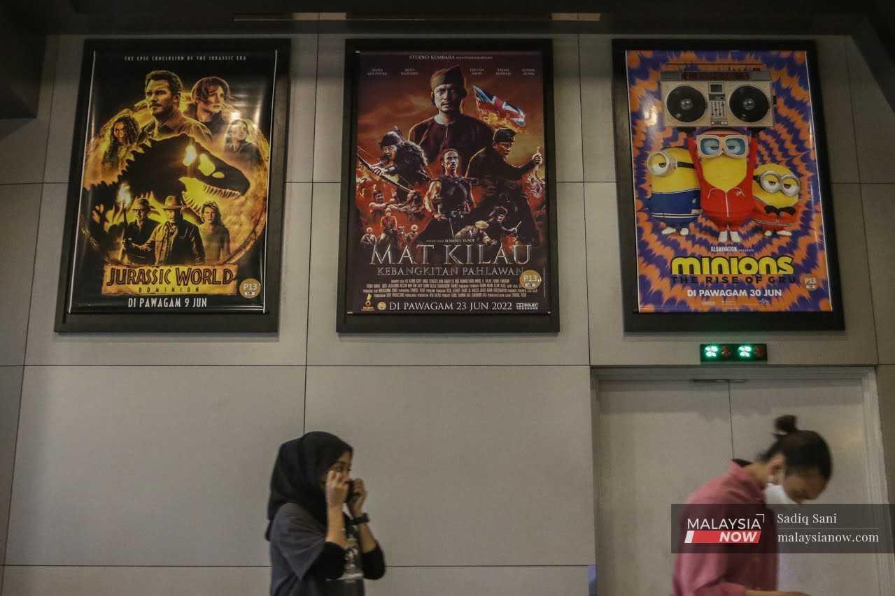 Moviegoers pass a poster for 'Mat Kilau: Kebangkitan Pahlawan' at a cinema in Putrajaya. 

