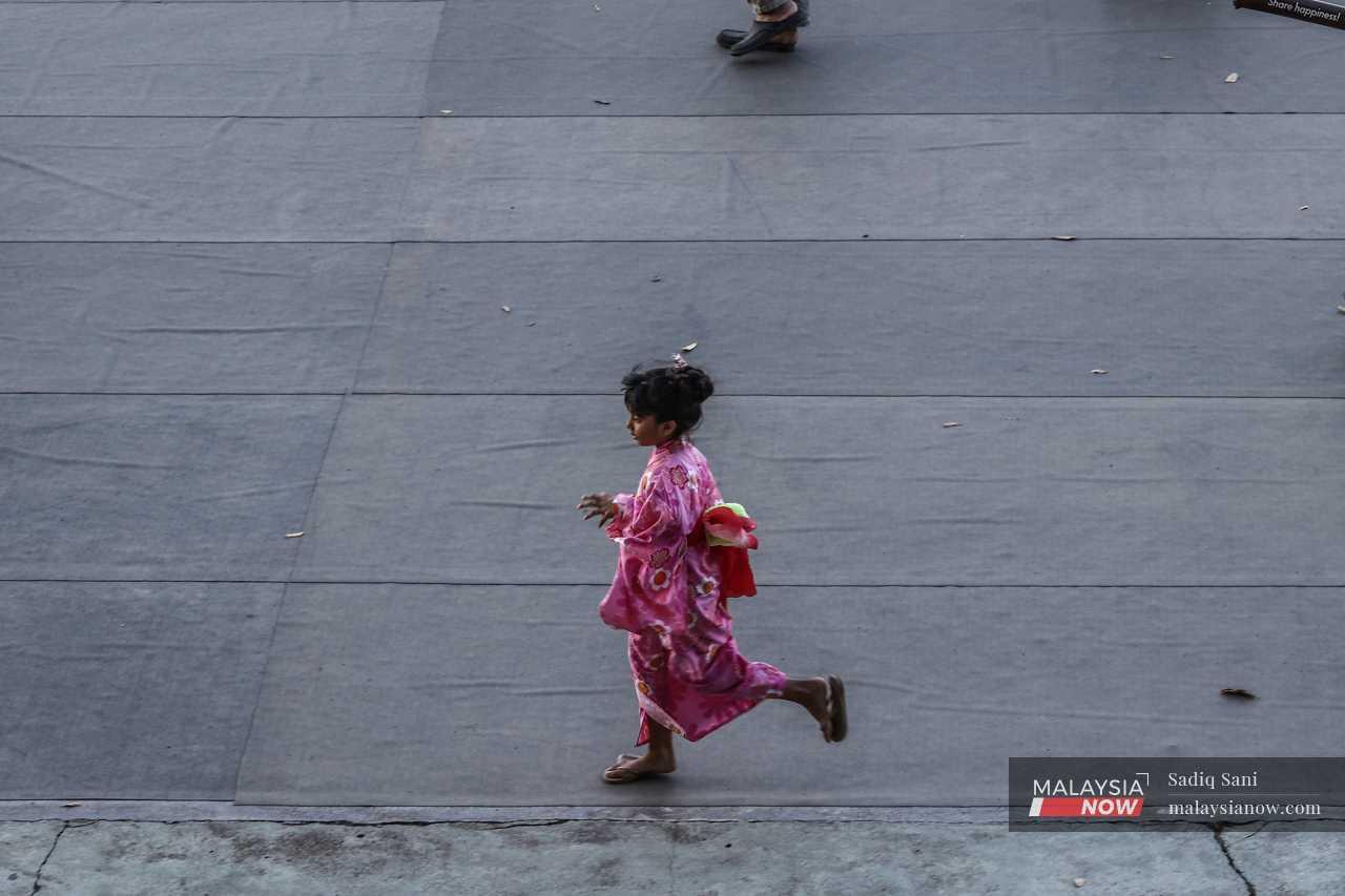 A child wearing a bright pink kimono runs inside the stadium compound.