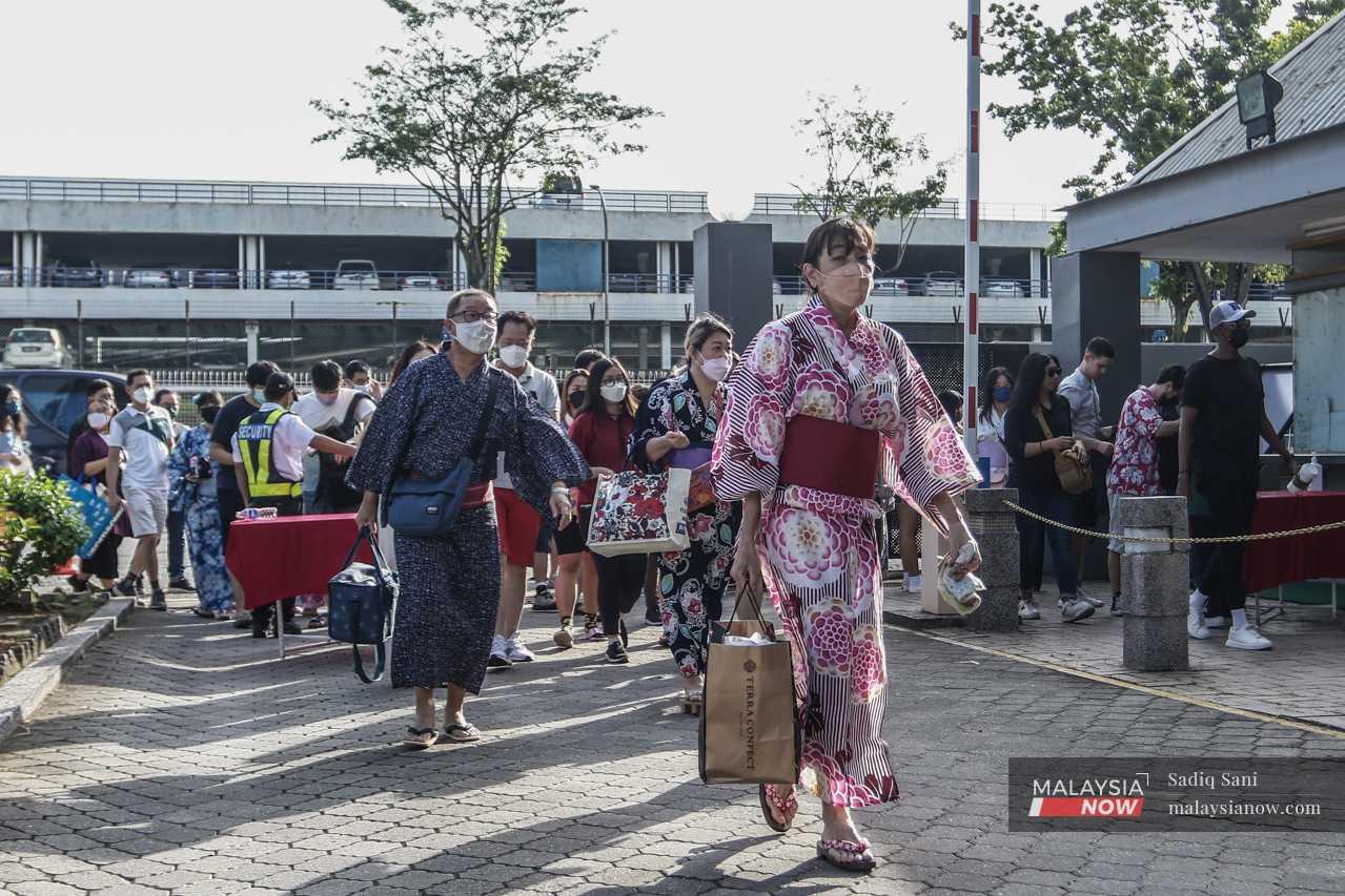 Participants wearing colourful yukata or light cotton kimonos, a traditional Japanese outfit for summer, enter the complex. 