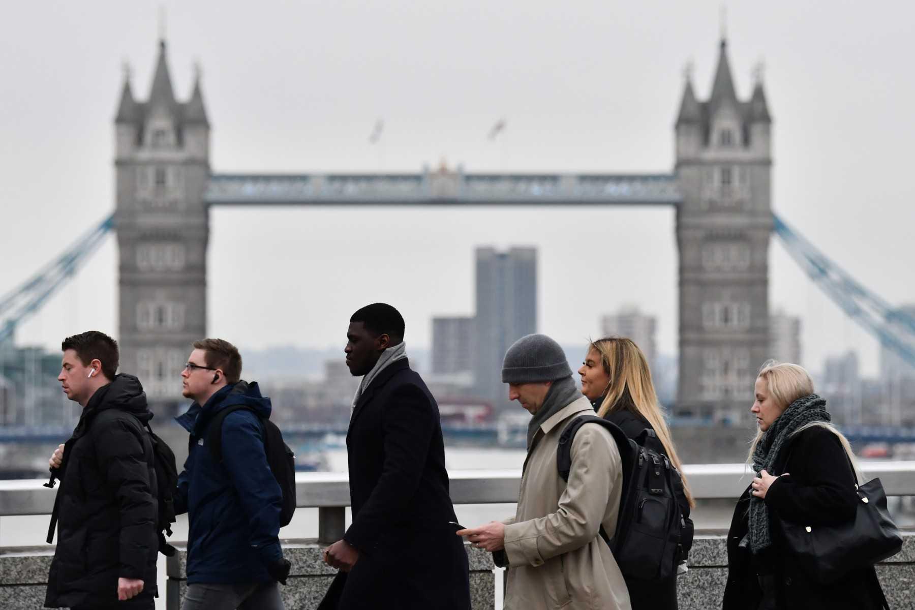 Pedestrians on their way to work cross the London Bridge backdropped by the Tower Bridge in central London on Jan 27. Photo: AFP