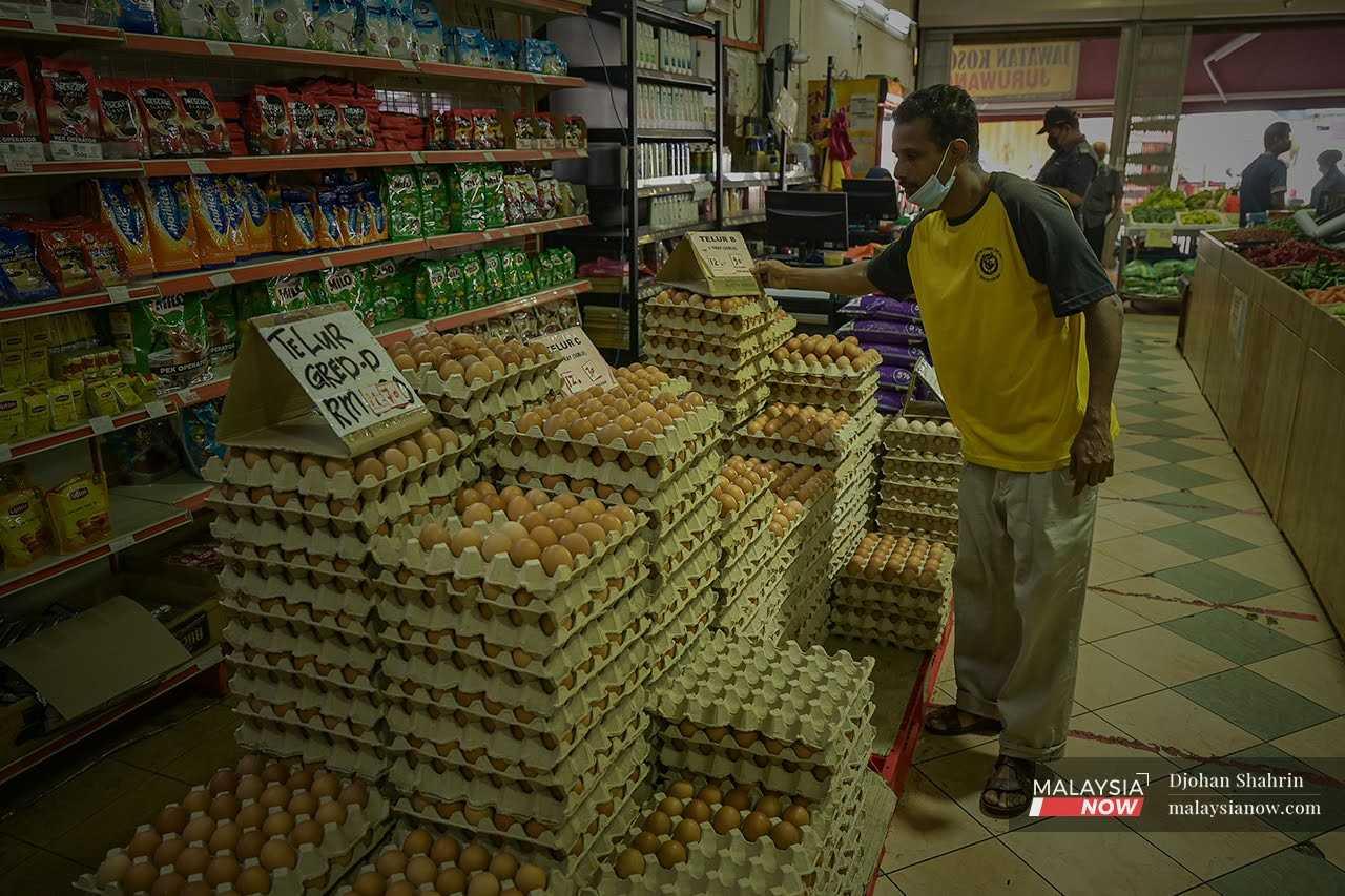 A worker places a sign showing the latest egg prices on a stack of chicken eggs at a dry goods store at the Jalan Chow Kit market in Kuala Lumpur. 
