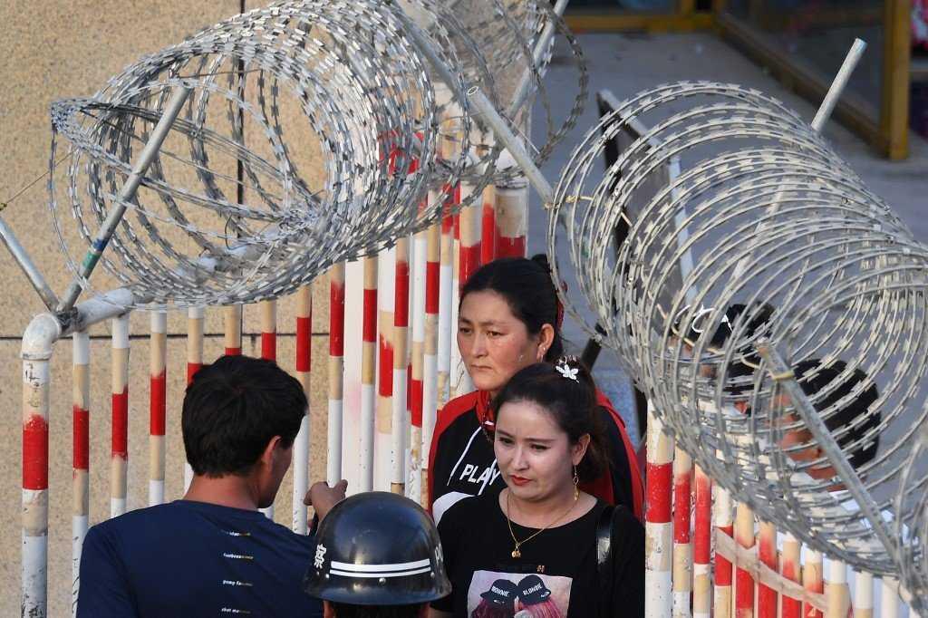 An Uighur woman (centre) passes through the entrance to a bazaar in Hotan, in China's northwest Xinjiang region. China has come under intense international criticism over its policies in Xinjiang. Photo: AFP
