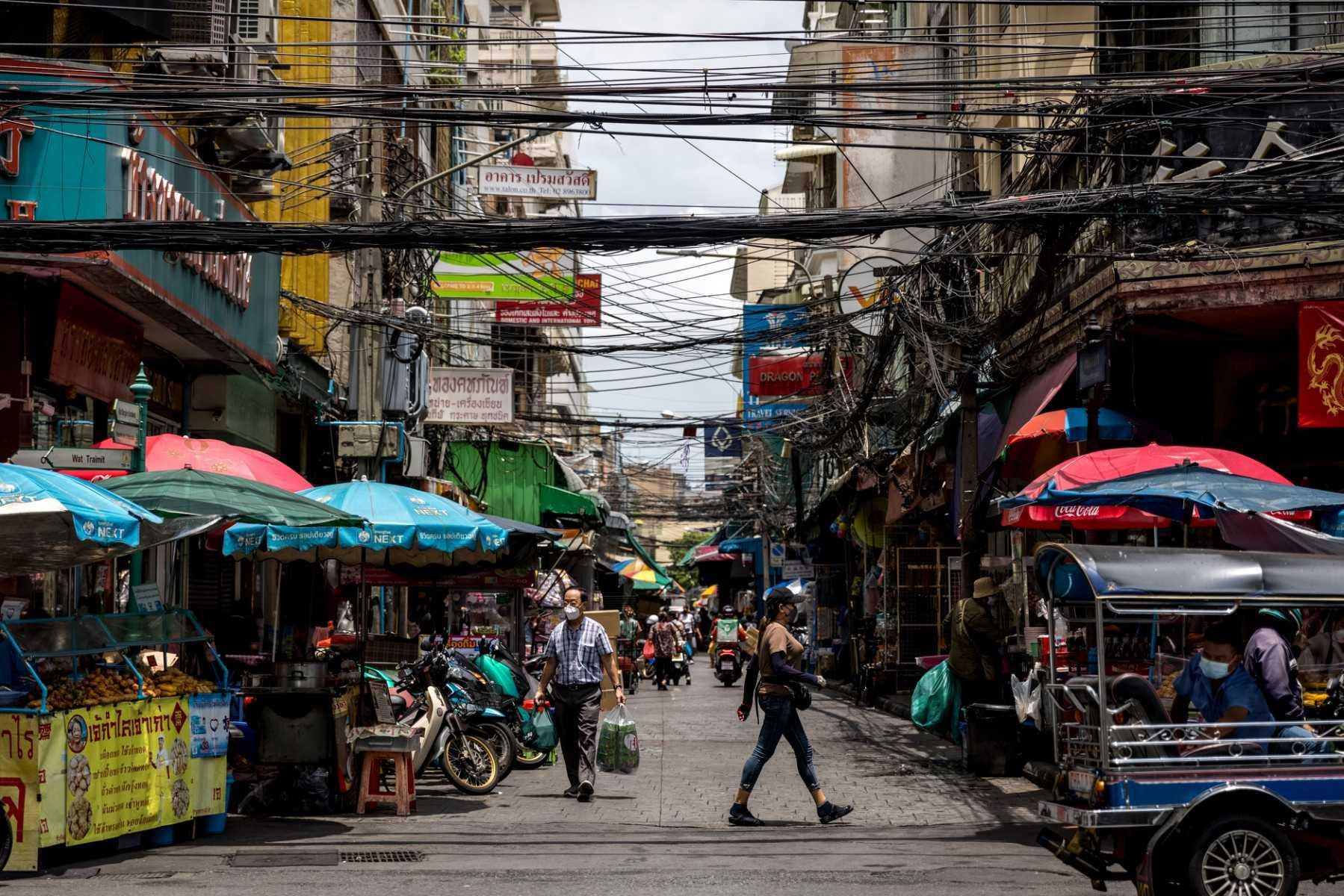 People walk along a street in the Chinatown area of Bangkok on May 28, 2021. The probe followed a mass alert from Apple Inc in November informing thousands of users of its iPhones, including in Thailand, that they were targets of 'state-sponsored attackers'. Photo: AFP 