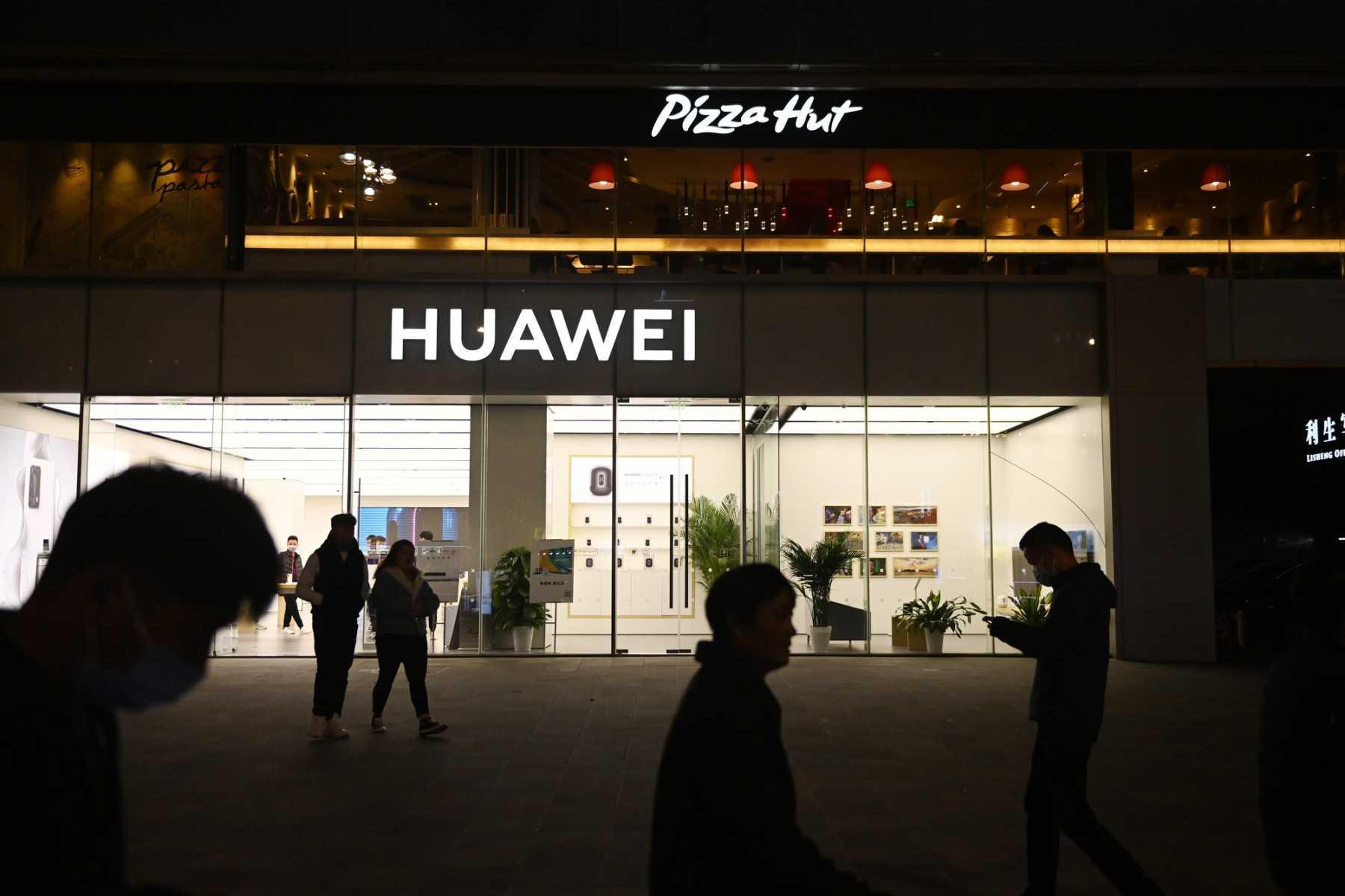People walk past a Huawei store below a Pizza Hut in Beijing on October 22, 2020. Photo: AFP